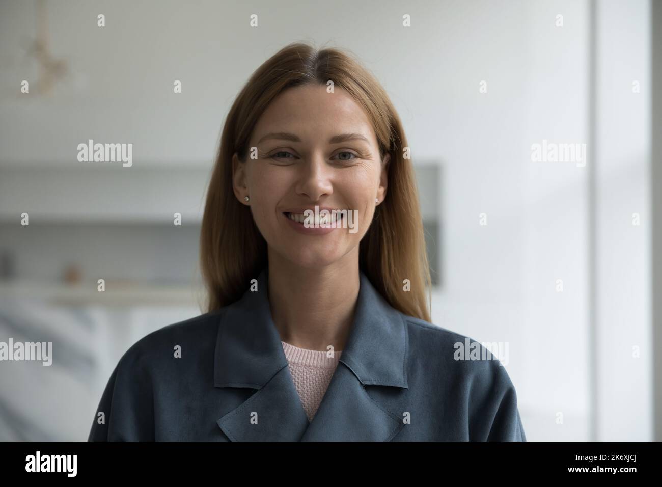 Testa ripresa donna ritratto in giaccone grigio posa in interni Foto Stock
