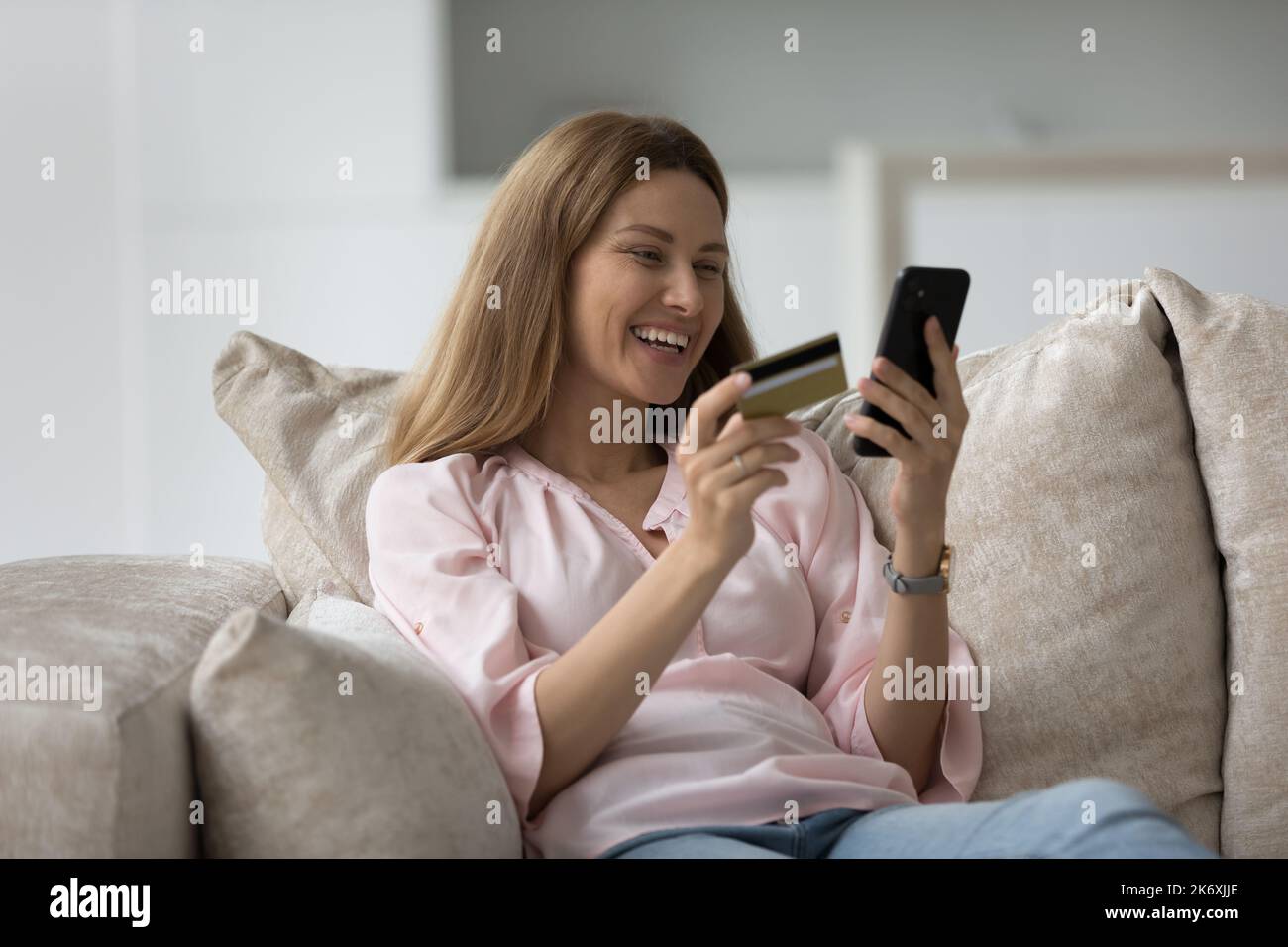 Donna felice tiene il cellulare e la carta di acquisto su internet Foto Stock
