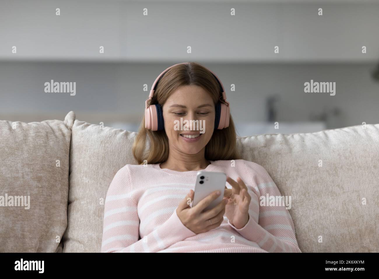 Donna in cuffie wireless tiene cellulare scegliere la canzone in playlist Foto Stock