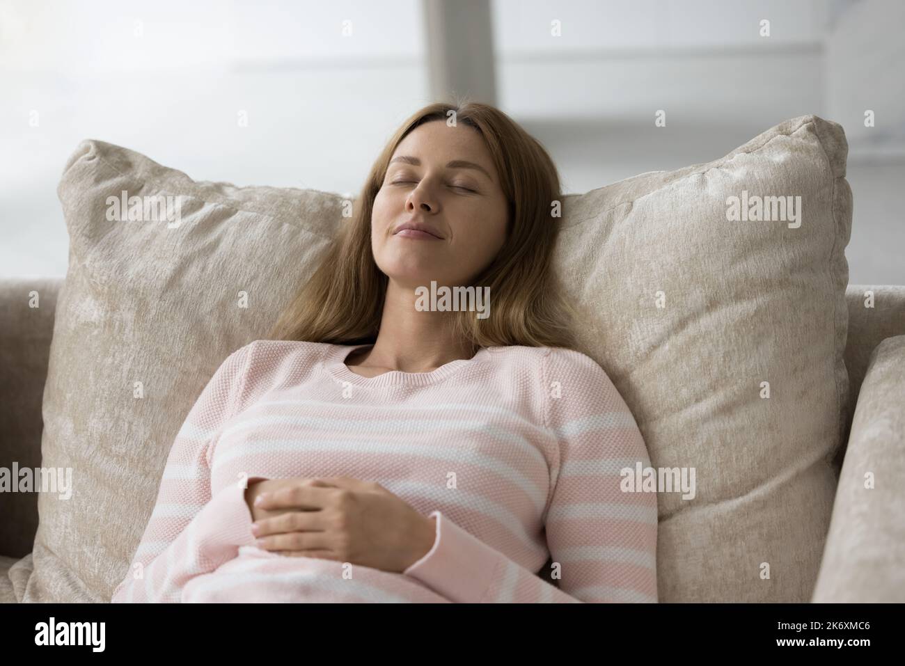 La giovane donna si snoze appoggiata su un comodo divano Foto Stock