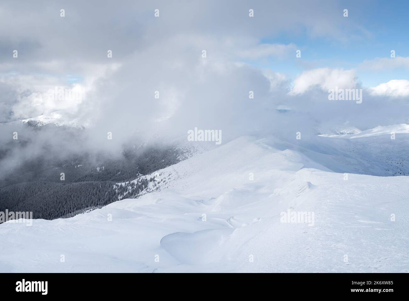 Clima invernale in montagna con nuvole basse e catena montuosa innevata Foto Stock