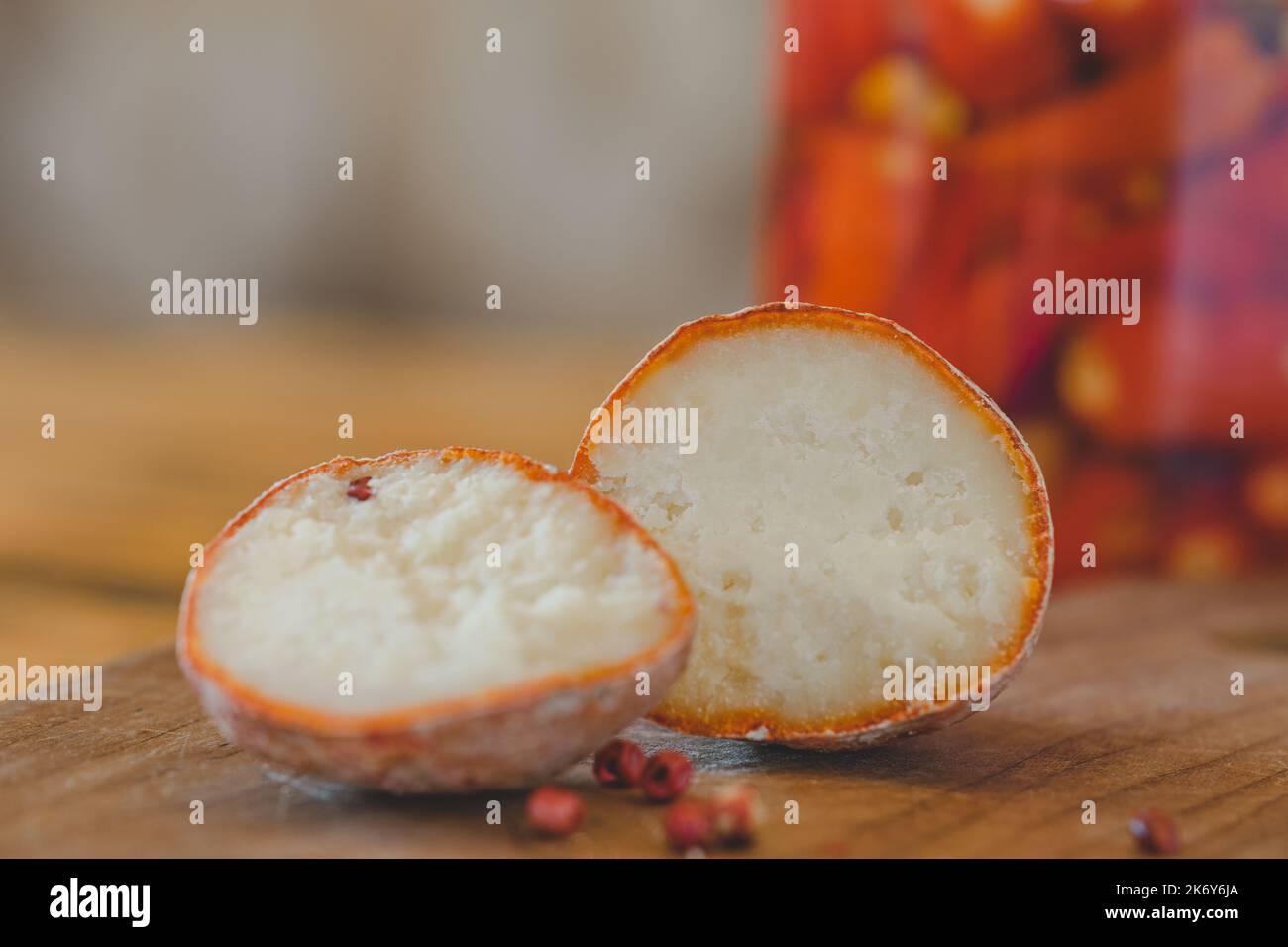 Una vista ravvicinata delle palle di belper knole con aglio e pepe rosa in cenere di legno. Formaggio svizzero. Formaggio lattico fermentato. E jalapeno in scatola sullo sfondo. SDOF Foto Stock