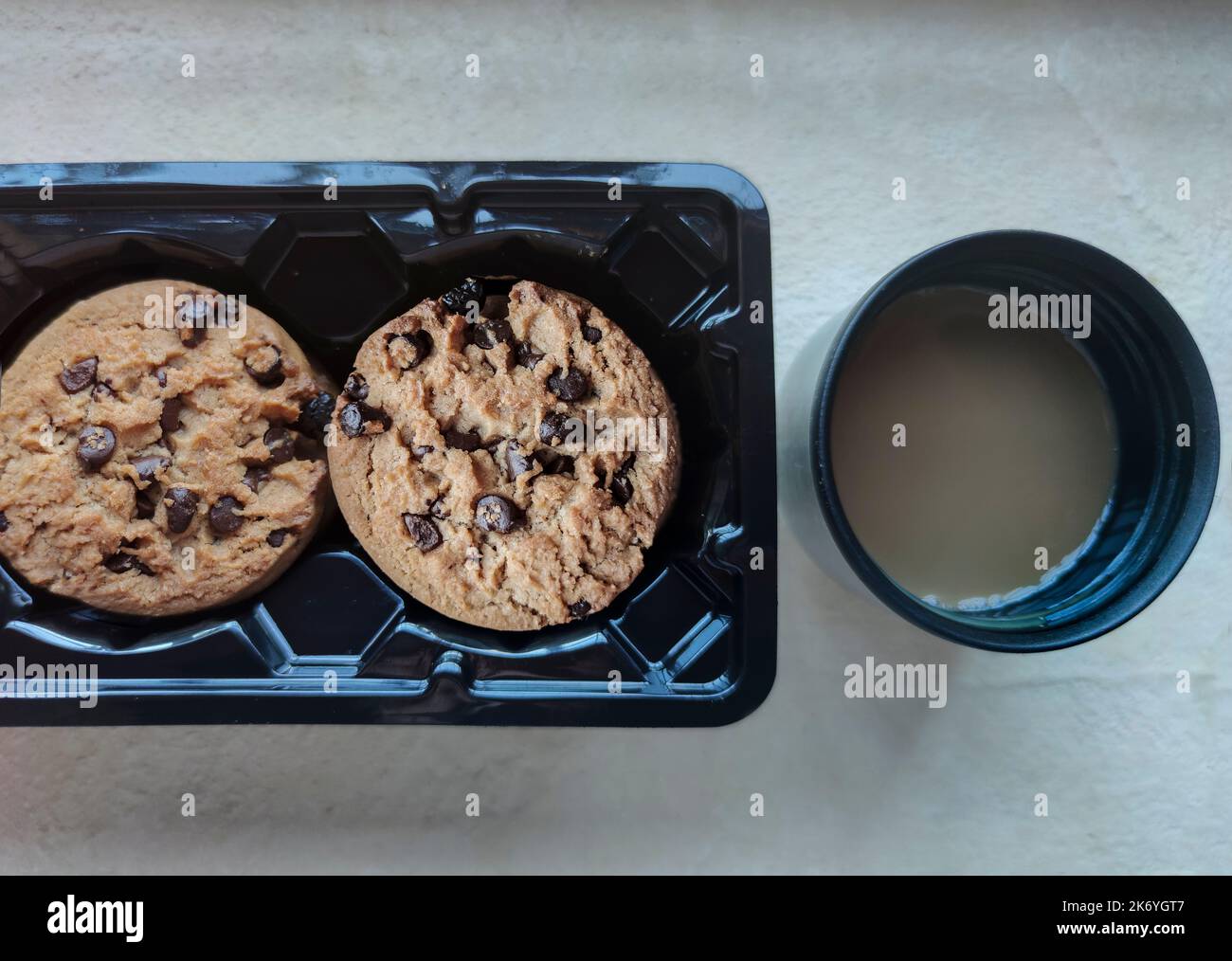 Biscotti con scaglie di cioccolato nella confezione e tazza da caffè in beuta sottovuoto. Concetto di caffè sul luogo di lavoro Foto Stock