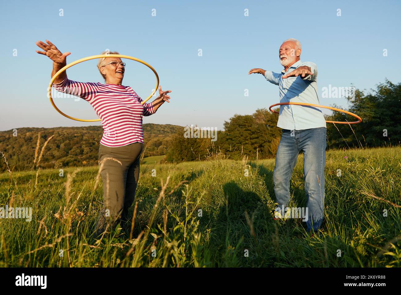 donna uomo esterno coppia anziana felice pensionamento insieme sorridente amore filatura esercizio cerchio maturo Foto Stock