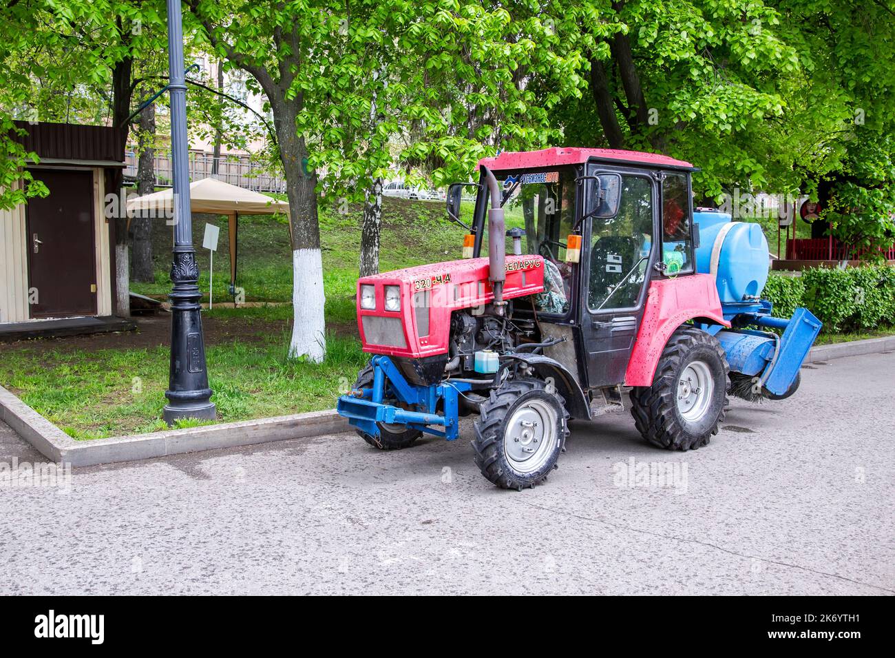 Samara, Russia - 20 maggio 2022: Trattore di attrezzatura speciale Bielorussia con un barile per l'acqua nel parco della città. Pulizia e cura del territorio e pla Foto Stock
