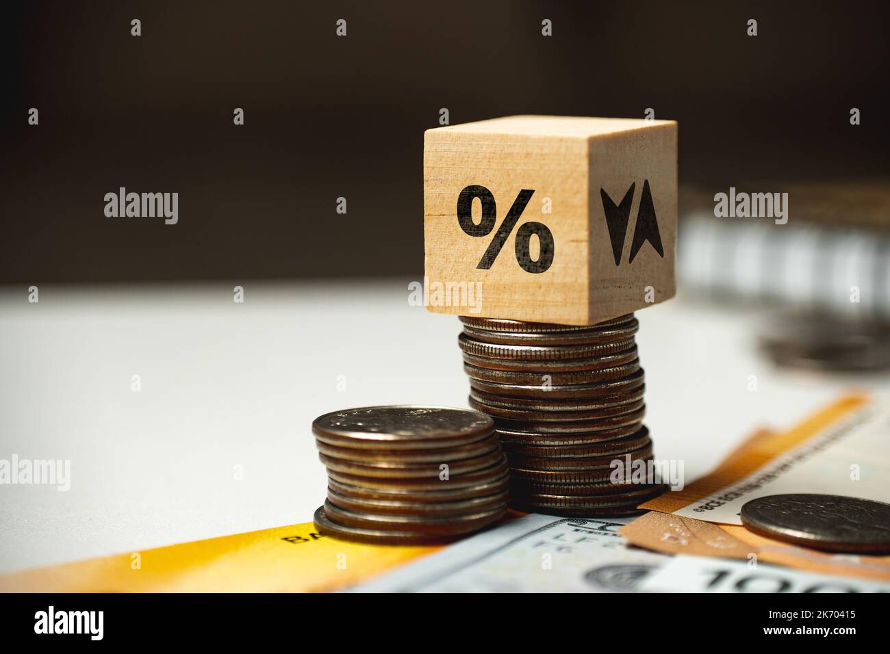 Il concetto di alzare e abbassare il tasso di interesse. Cubo su una pila di monete e altri soldi. Foto Stock