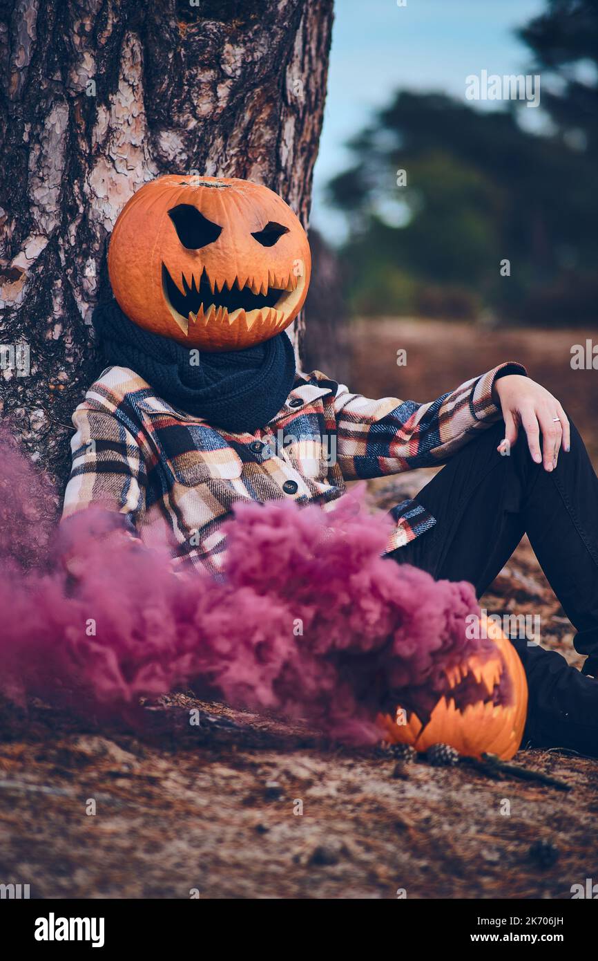 Persona con zucca per testa e bomba di fumo. Foto di alta qualità Foto Stock