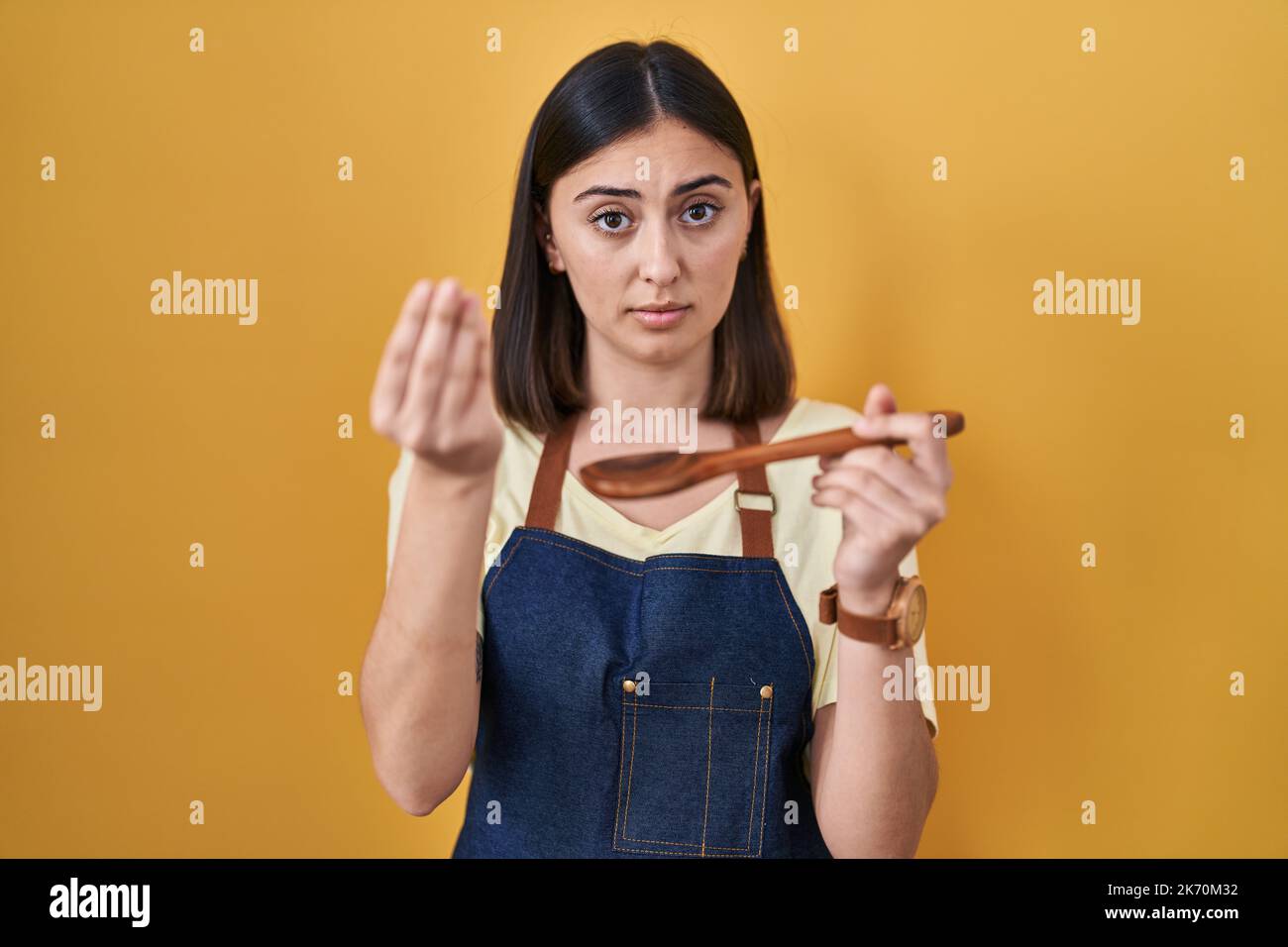 Ragazza ispanica mangiare sano cucchiaio di legno facendo gesto italiano  con mano e dita espressione fiduciosa Foto stock - Alamy