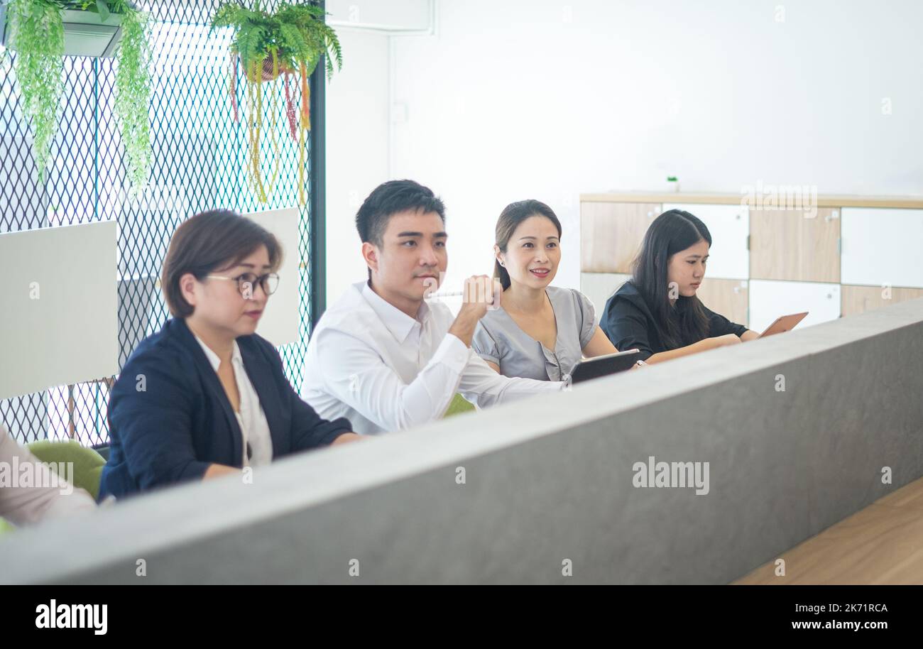 Persone aziendali sedute di fila che partecipano a una sessione di formazione in uno spazio di lavoro congiunto. Foto Stock