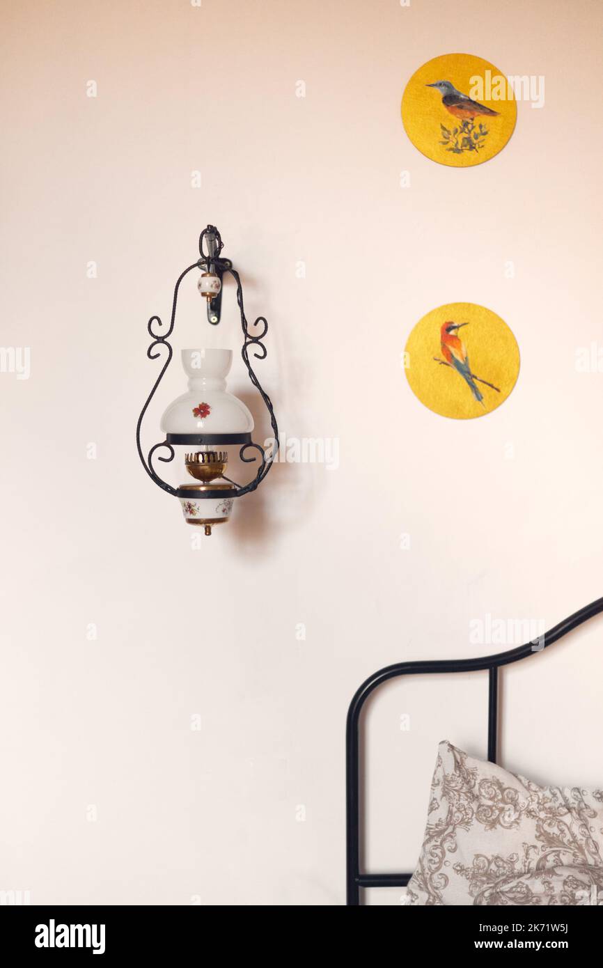 L'interno di un vecchio edificio, una stanza con una lampada al letto e disegni di uccelli. Foto verticale. Foto Stock