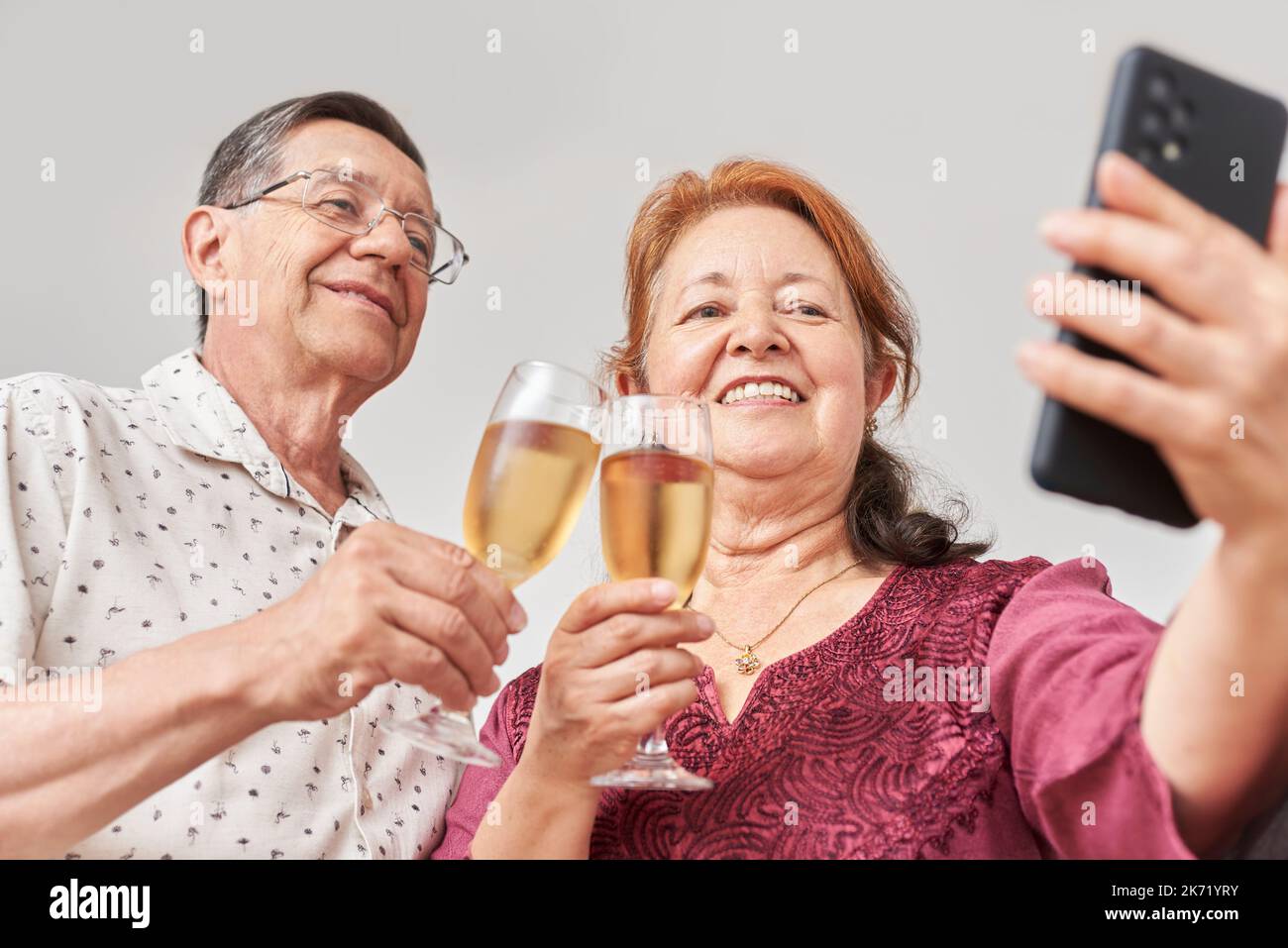 Felice coppia latina che parla con una videochiamata o che fa un selfie con uno smartphone mentre brinda, festeggia insieme. Concetto: Comunicazione tec Foto Stock