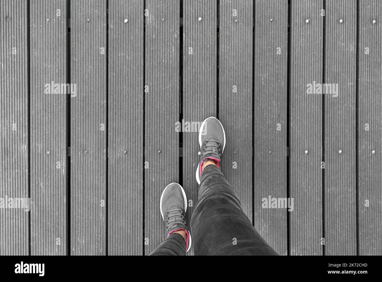 Gambe in sneaker su piattaforma in legno. Foto Stock