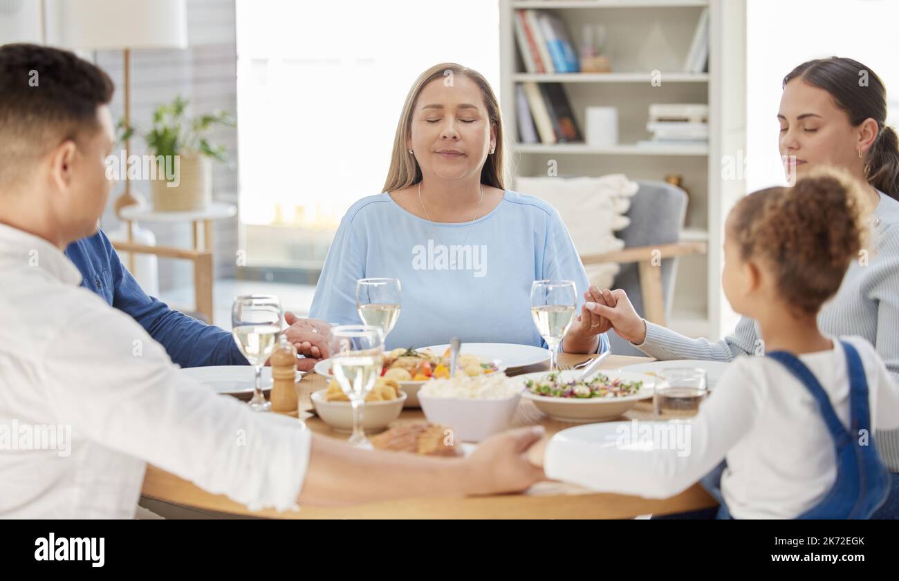 Benedica le mani che hanno preparato il pasto. una bella famiglia benedice il cibo con una preghiera al tavolo insieme a casa. Foto Stock