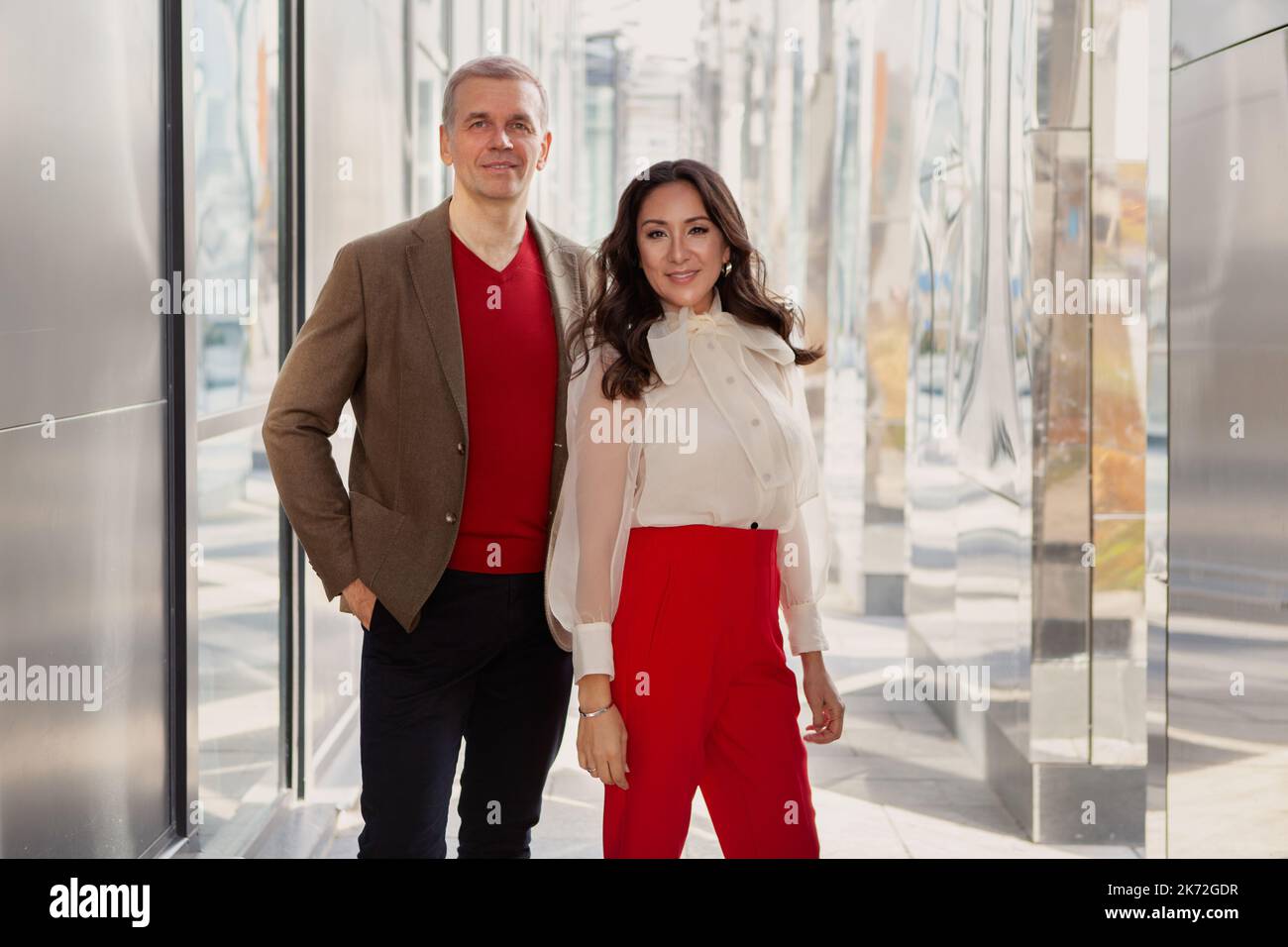 Abbigliamento alla moda, business casual. Uomo d'affari rispettabile che indossa giacca e maglione marrone e Donna in pantaloni rossi e un look elegante camicia bianca Foto Stock