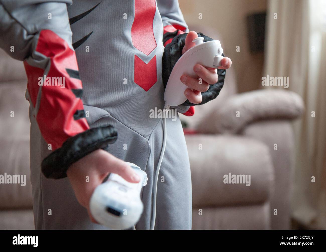 Ragazzo che indossa un abito super eroe e che tiene un Nintendo Wii Remote e Nunchuck Foto Stock