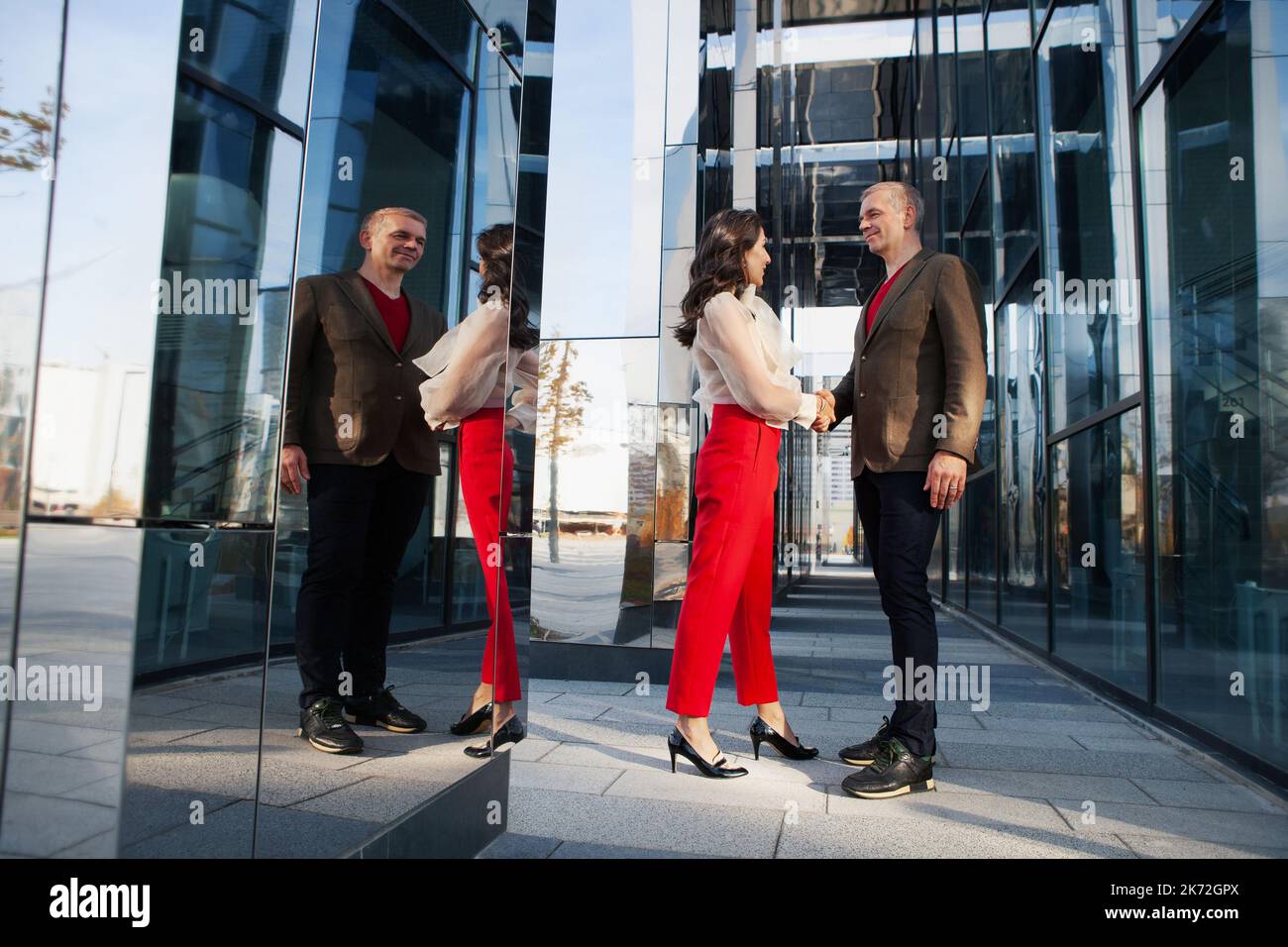 Collaborazione o conclusione riuscita dei partner commerciali di transazione. Donna alla moda e un elegante uomo d'affari stretta di mano sulla strada vicino al Foto Stock