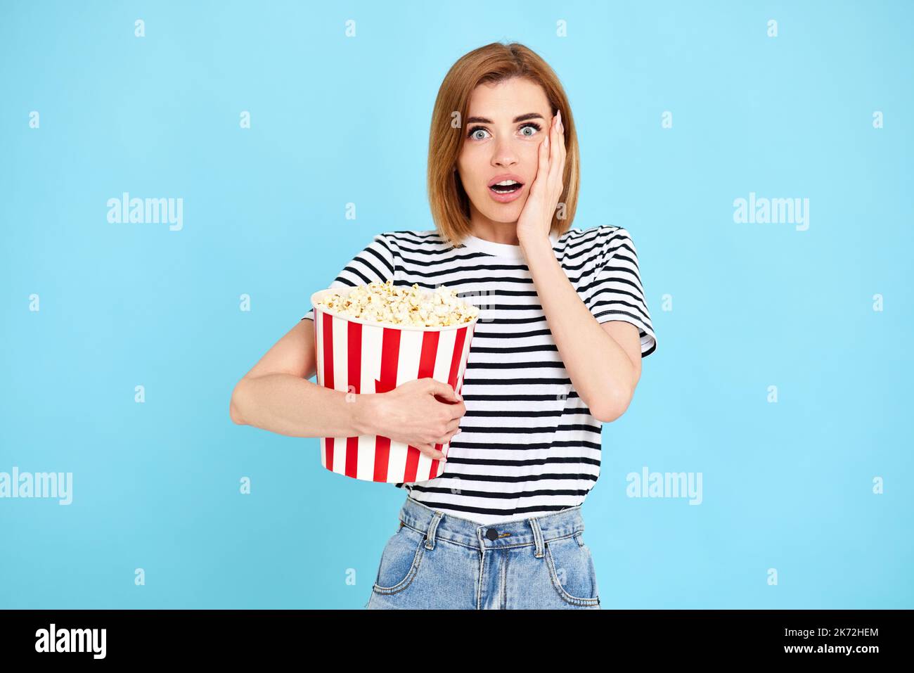 donna che guarda film, che tiene secchio di popcorn Foto Stock