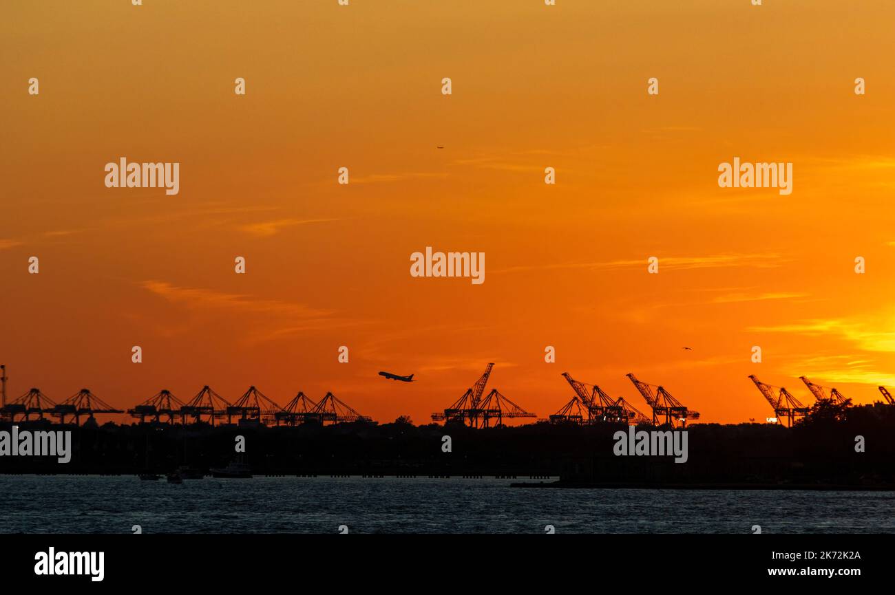 Silhouette di Jersey Port gru e aereo decollo dall'aeroporto di Newark, Jersey, USA Foto Stock