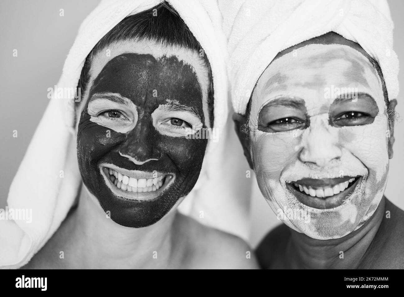 Donne anziane multirazziali che fanno il trattamento di bellezza usando la maschera della pelle - fuoco sugli occhi femminili di sinistra - montaggio in bianco e nero Foto Stock