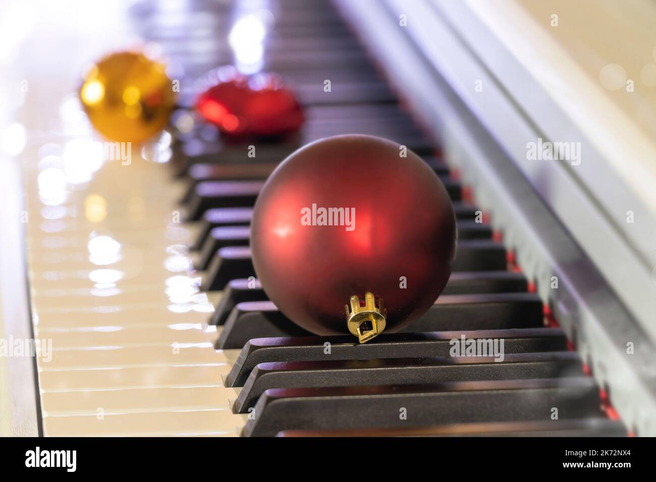 messa a fuoco morbida su un piano tasti con una palla rossa di natale. concetto di musica di capodanno o di natale Foto Stock