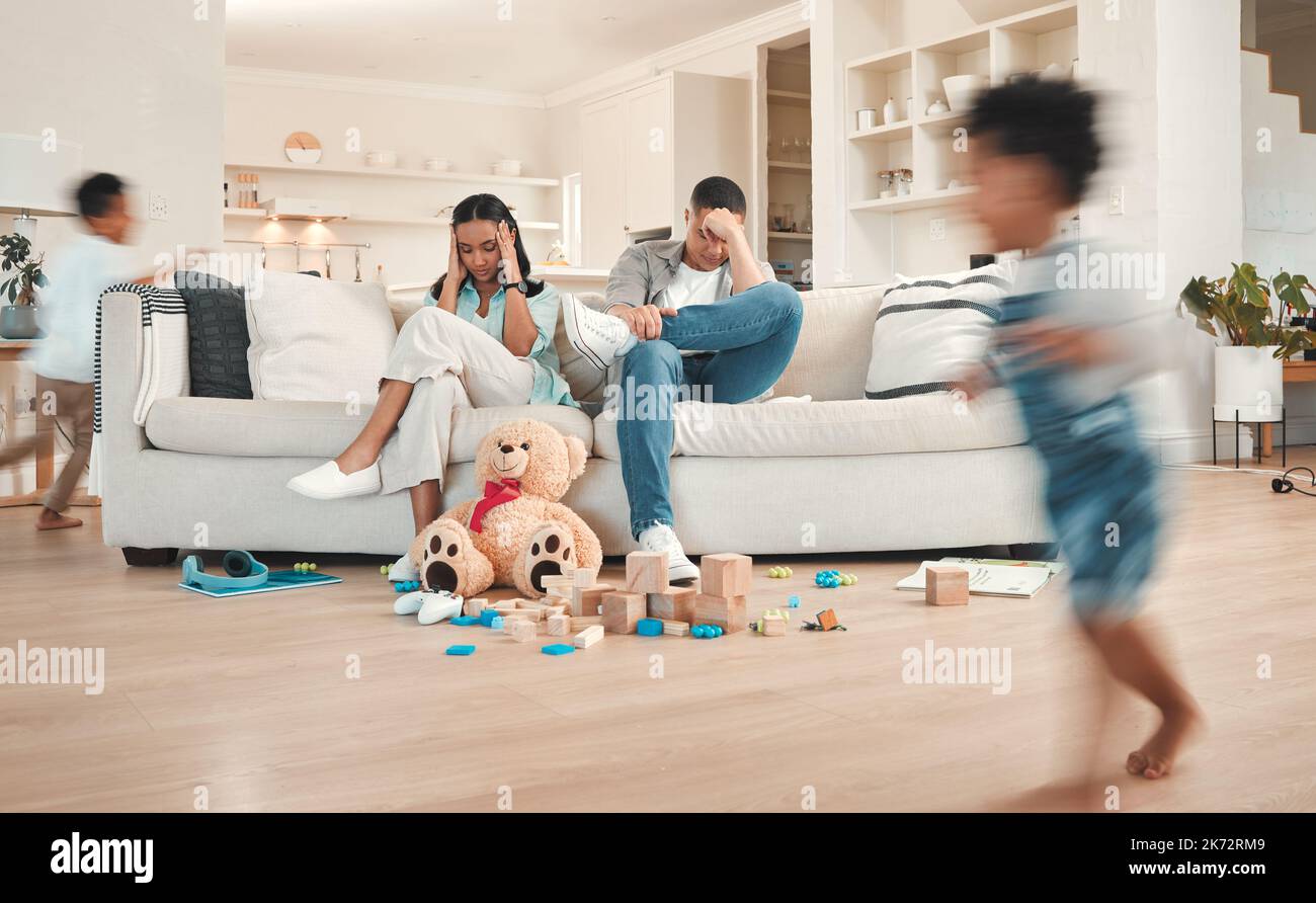 Mamma e papà hanno bisogno di qualche tempo noi. una giovane coppia che guarda stressato a casa mentre i loro bambini giocano intorno a loro. Foto Stock
