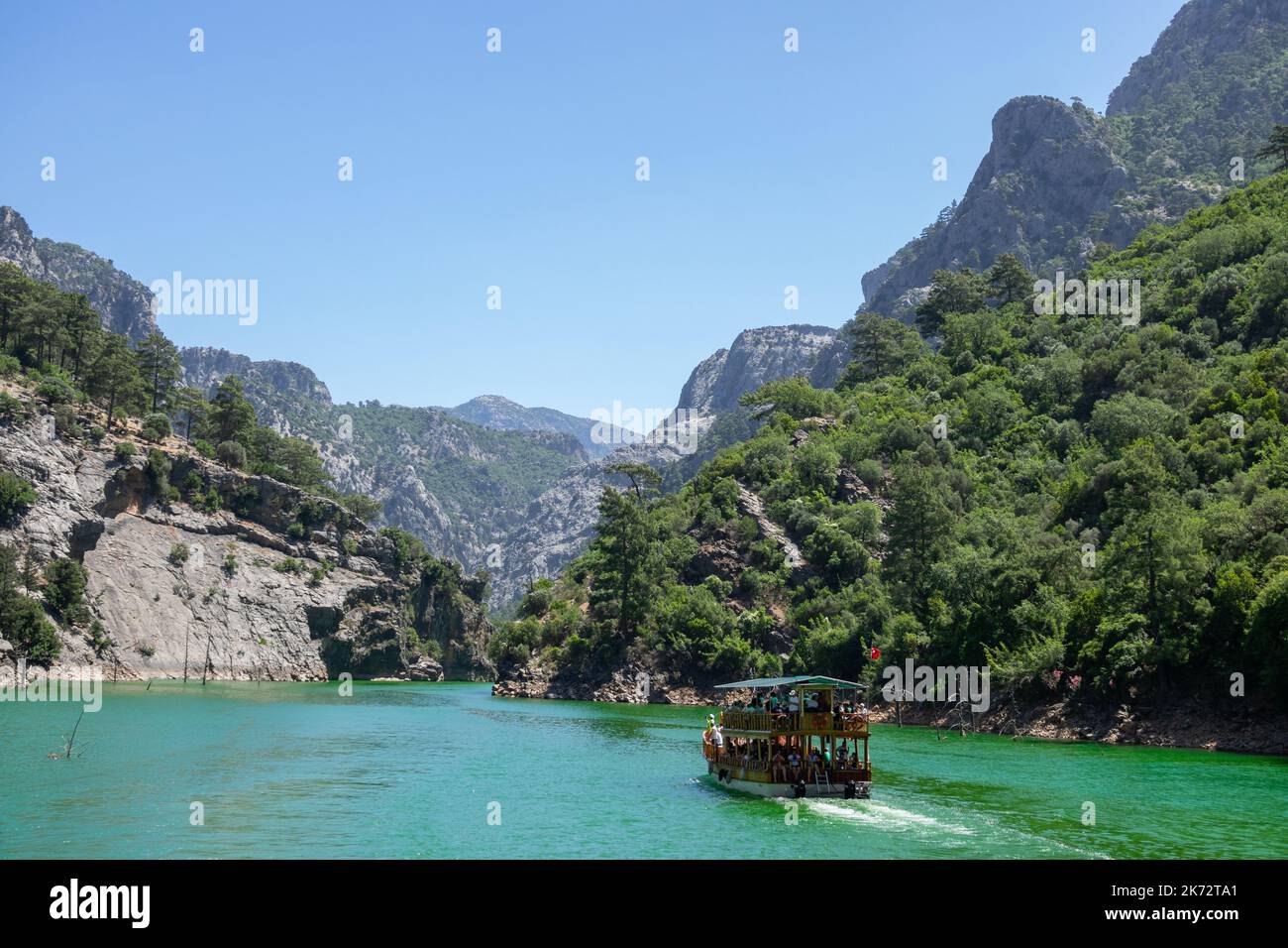 Manavgat, Turchia - 05 giugno 2019: Le persone su uno yacht turistico galleggiano sul lago tra le scogliere di montagna del canyon verde. Paesaggio del canyon verde, ma Foto Stock