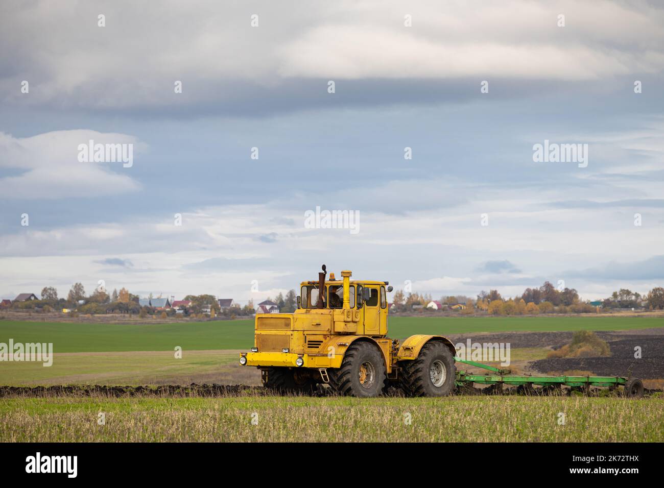 vecchio modello di trattore che lavora sul campo. un trattore grande aratri il terreno Foto Stock