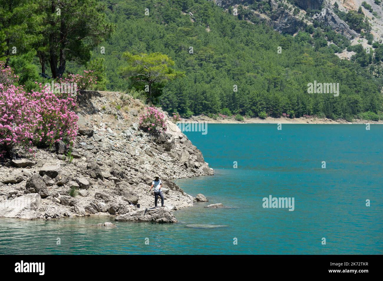 Manavgat, Turchia - 05 giugno 2019: Un pescatore cattura i pesci su un lago tra le scogliere di montagna nel Canyon Verde Foto Stock