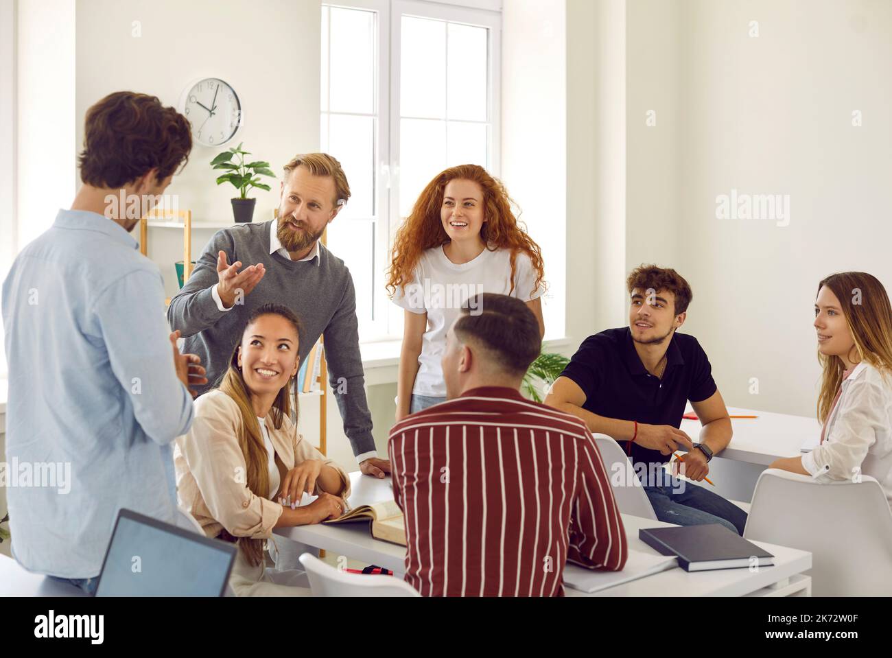 Un insegnante maschile intelligente e amichevole discute con gli studenti spiegando materiale durante la lezione sui corsi. Foto Stock