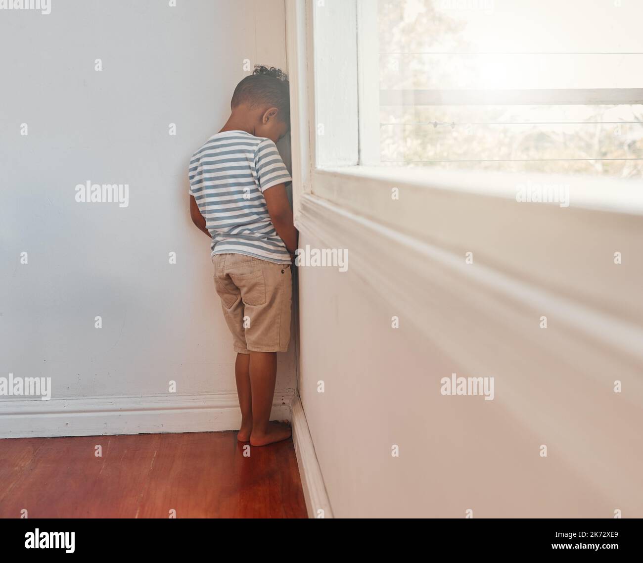 Devono imparare che le loro azioni hanno conseguenze. un ragazzino irriconoscibile di fronte al muro e come punizione in una stanza a casa. Foto Stock