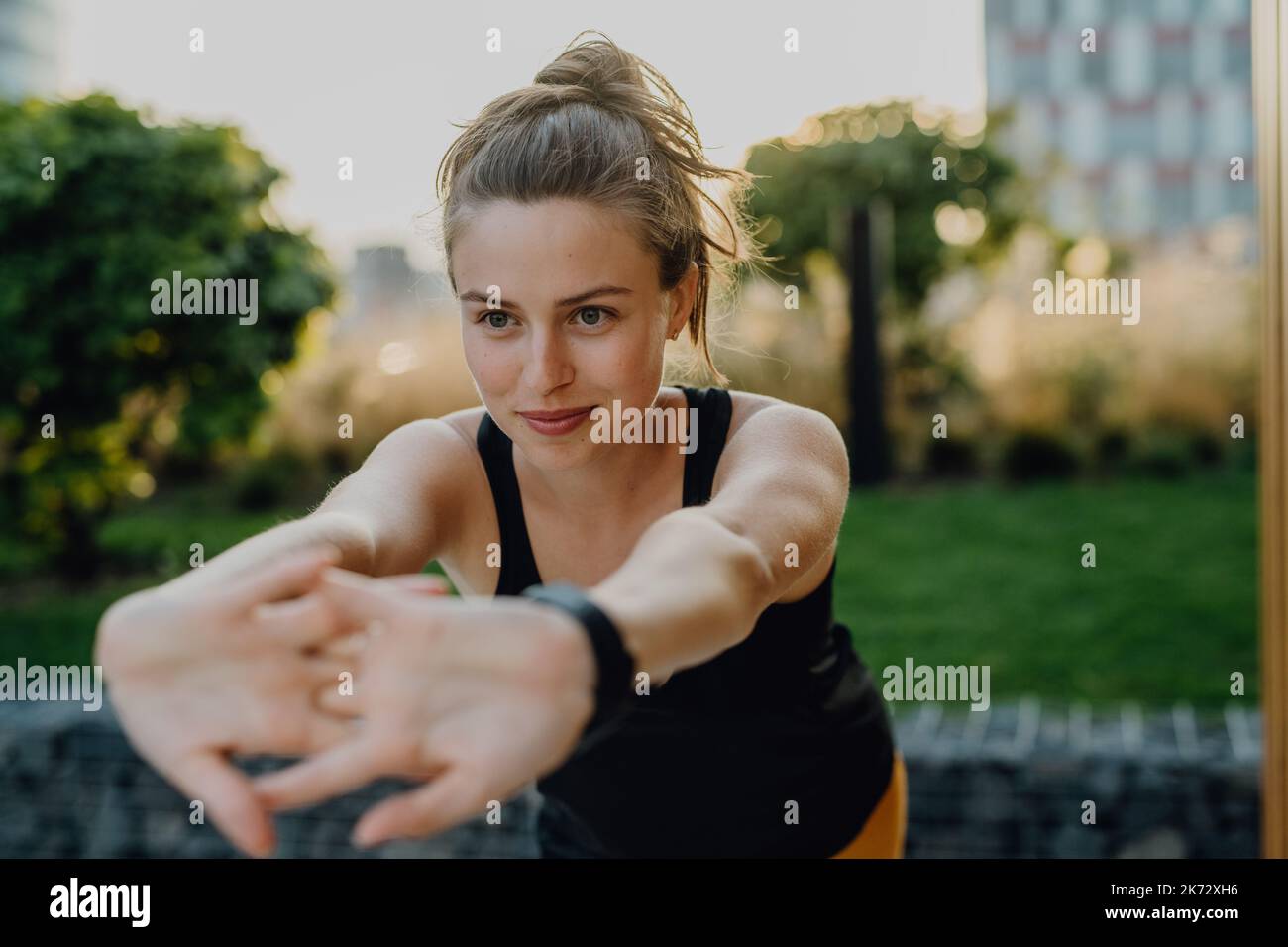 Giovane donna che fa stretching in città, preparandosi per la corsa, stile di vita sano e concetto di sport. Foto Stock