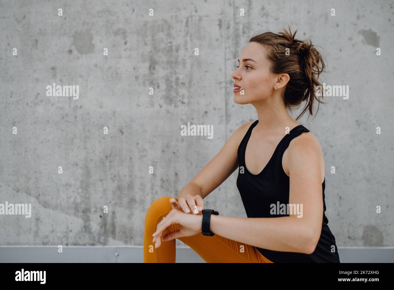 Giovane donna che fa stretching in città, preparandosi per la corsa, stile di vita sano e concetto di sport. Foto Stock