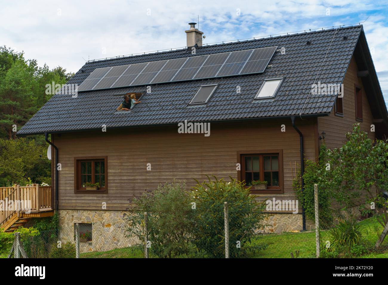 Padre con suo figlio che guarda dai lucernari i pannelli solari sul loro tetto. Energia alternativa, risparmio di risorse e stile di vita sostenibile Foto Stock