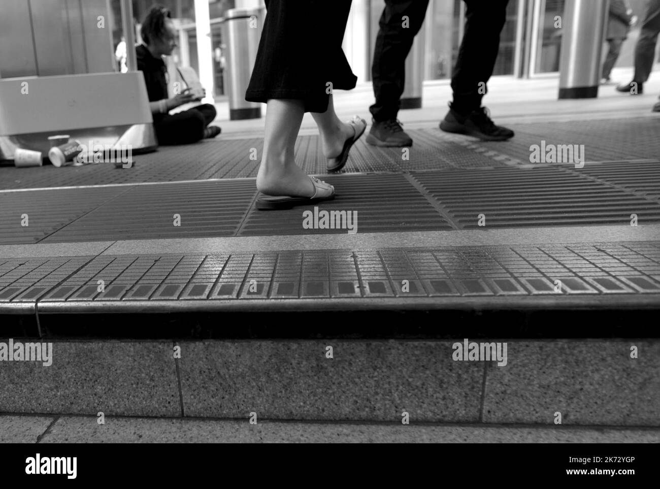 Londra, Inghilterra, Regno Unito. La gente che cammina davanti a una persona senza tetto che implora sui gradini della stazione della metropolitana Victoria Foto Stock