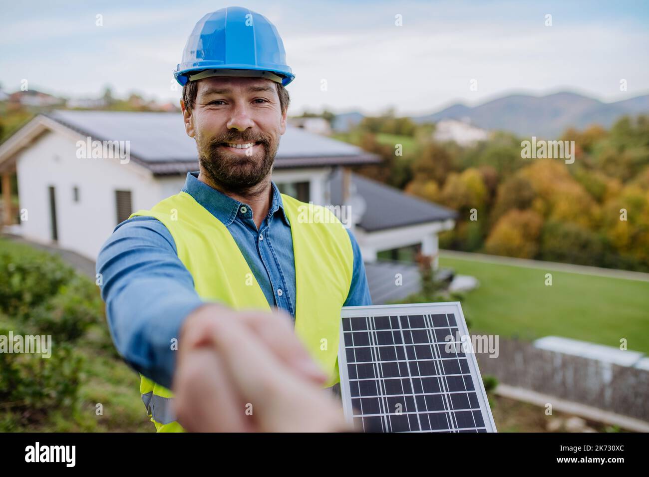 Sorridente handyman, installatore pannelli fotovoltaici scuotendo la mano con il proprietario di casa. Foto Stock