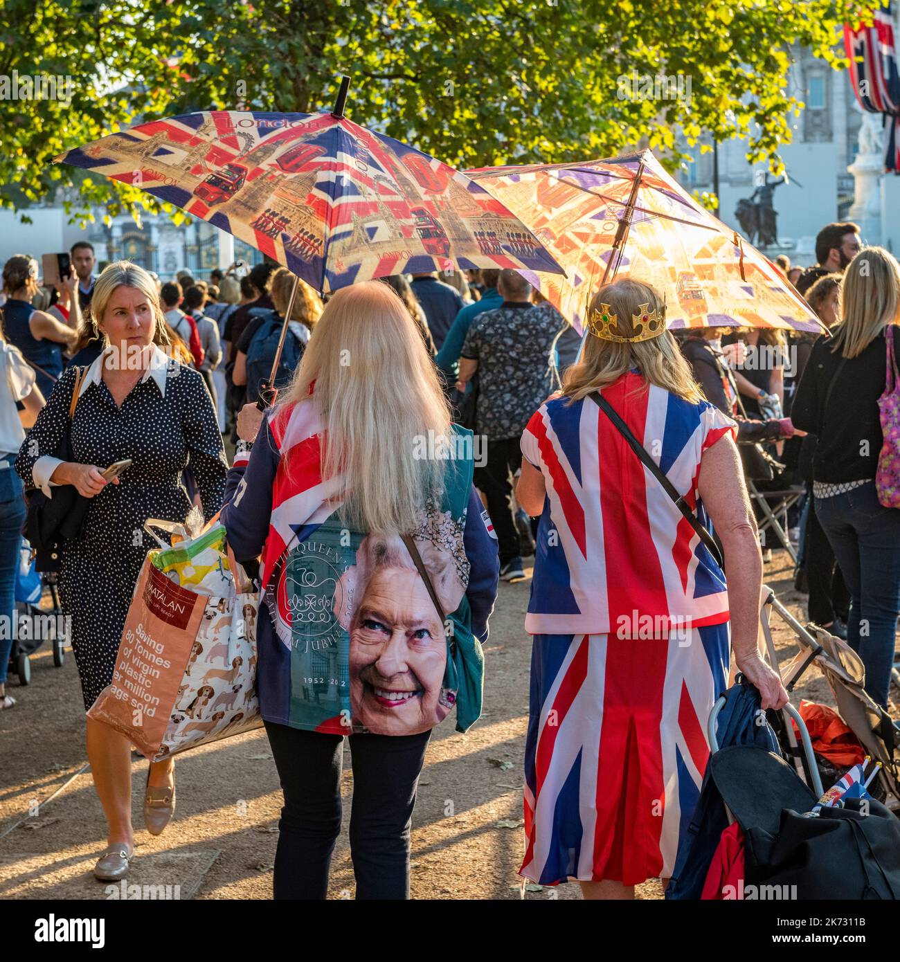Due donne che indossano abiti da Union jack e che trasportano ombrelli rossi bianchi e blu, al funerale della Regina Elisabetta II, a St James's Park, Londra, Regno Unito Foto Stock