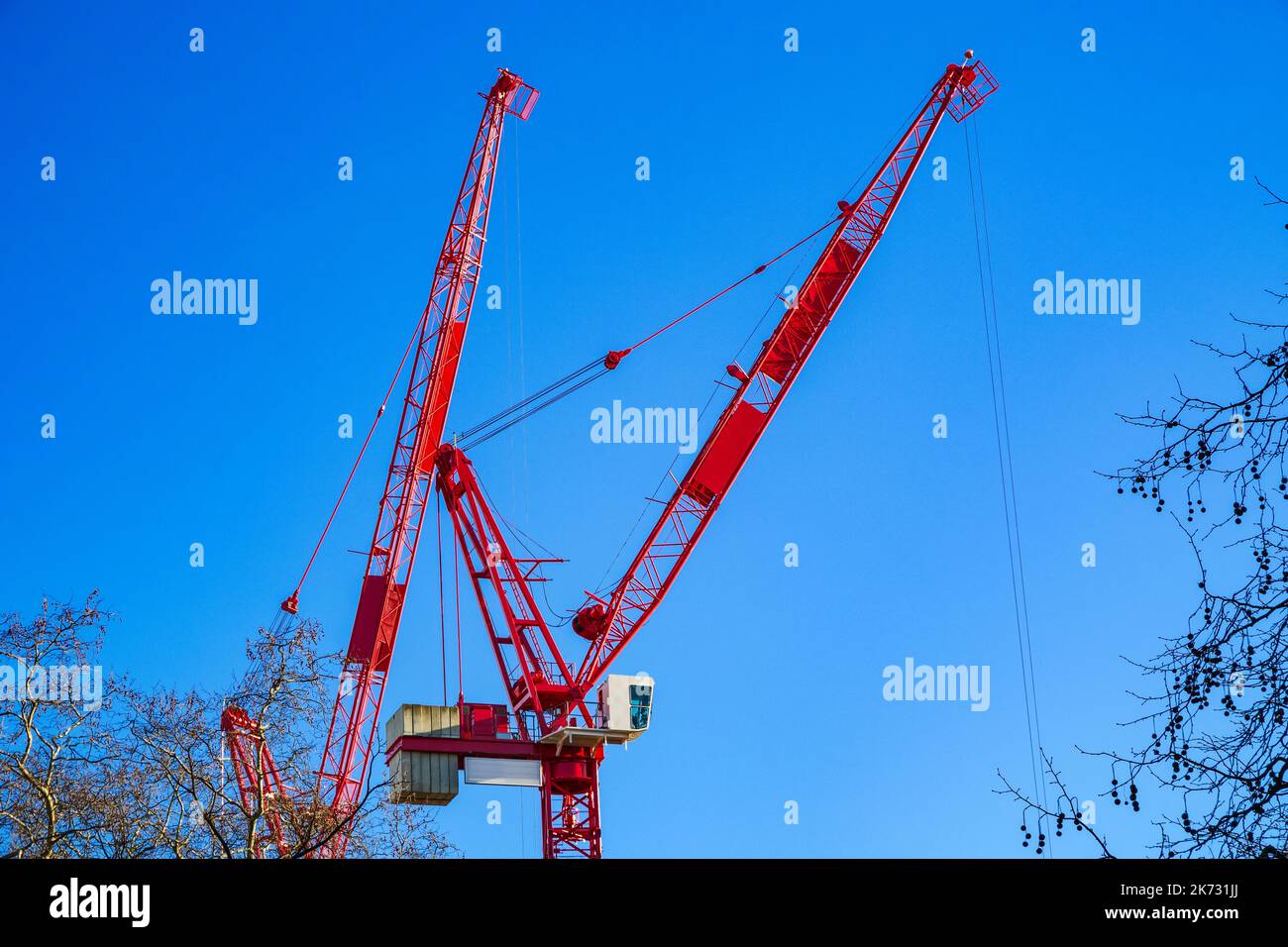 Due gru a torre contro un cielo senza nuvole in un cantiere di costruzione a Londra, Inghilterra Foto Stock