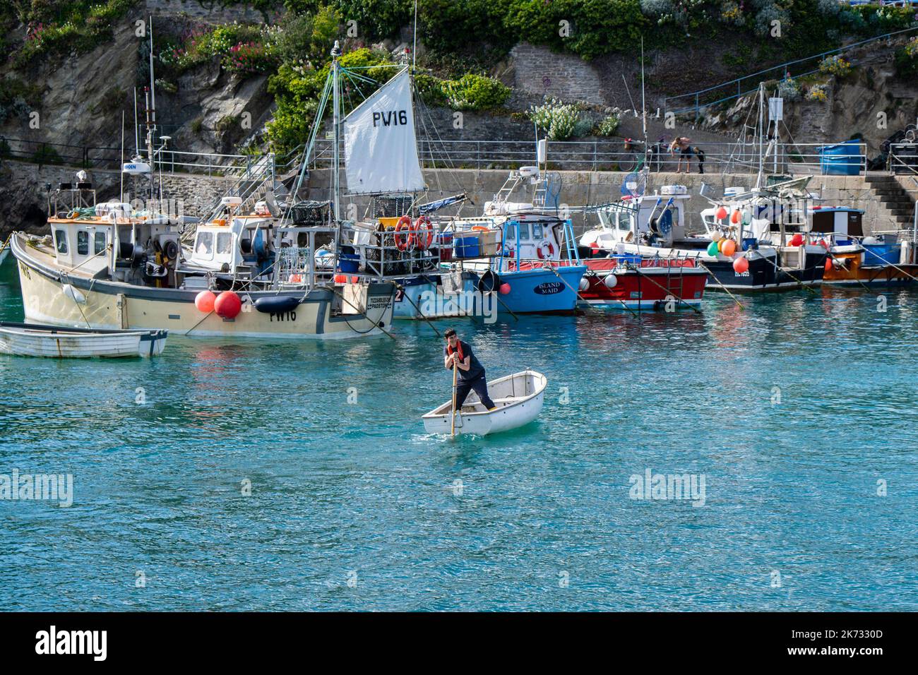 Un uomo che scolpisce la poppa di un gommone nel pittoresco porto di Newquay, in Cornovaglia, nel Regno Unito. Foto Stock