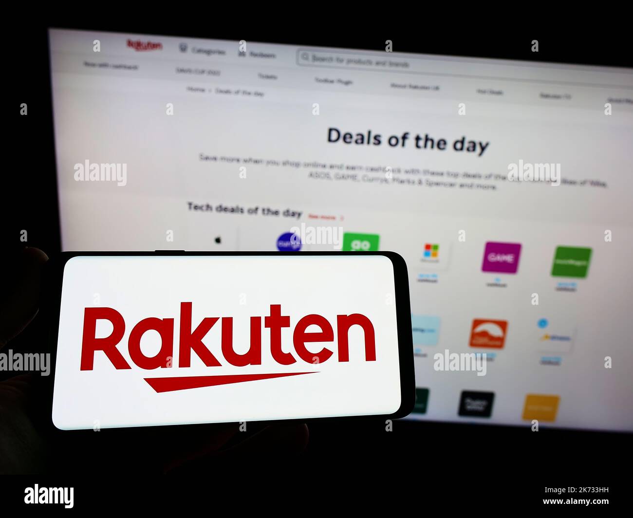 Persona che tiene in mano uno smartphone con il logo della società giapponese di e-commerce Rakuten Group Inc. Sullo schermo di fronte al sito Web. Messa a fuoco sul display del telefono. Foto Stock