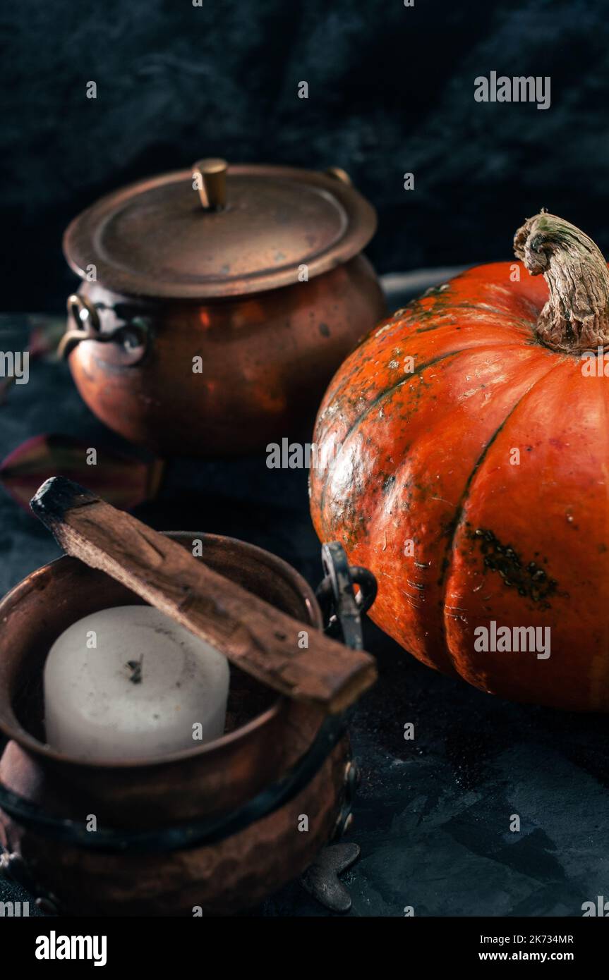 Una zucca squash e rame o pentole di ottone strega con candele e palo santo incence sul nero scuro blu textured copia sfondo spazio halloween Foto Stock