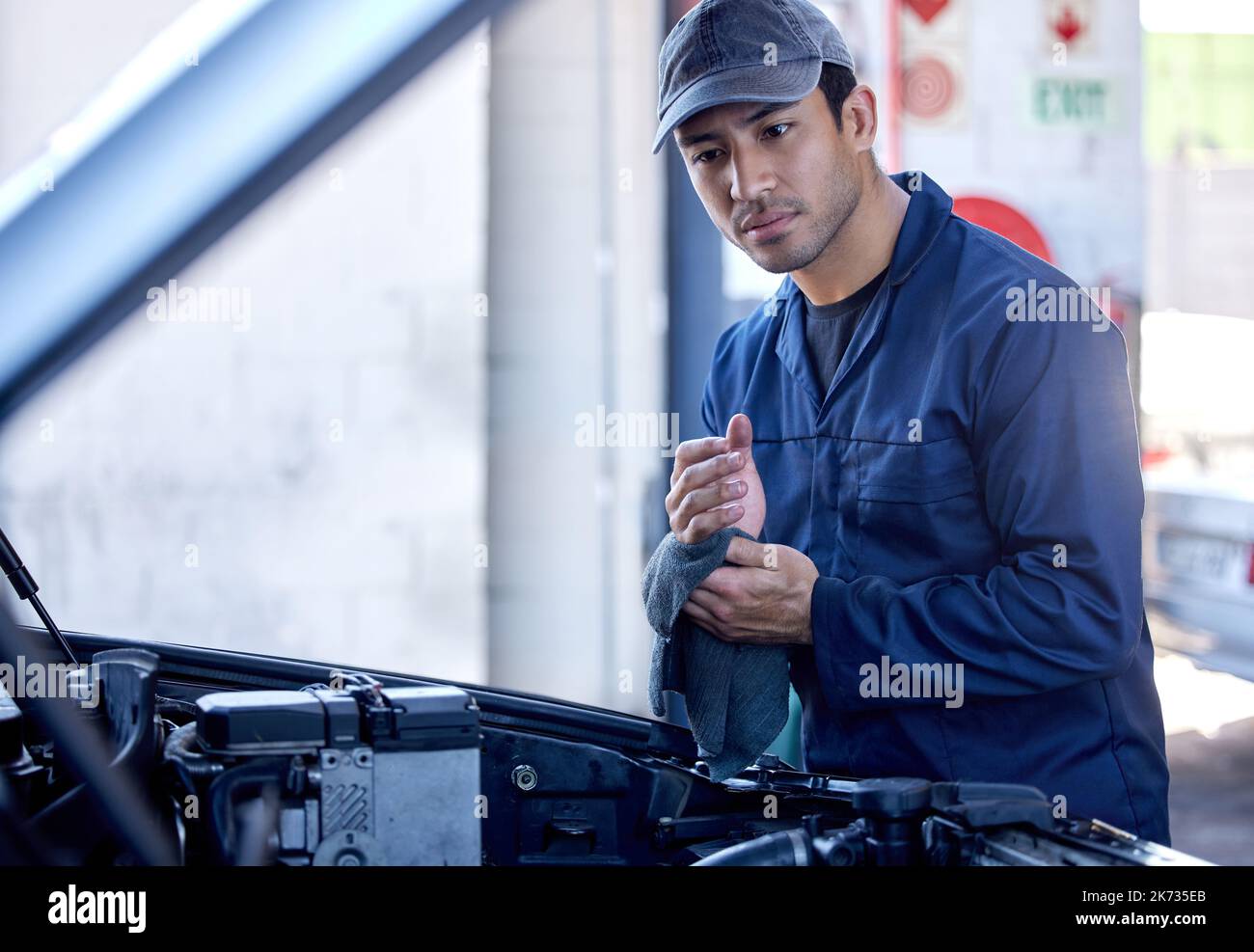 Tutto fatto. un bel giovane meccanico maschile che lavora sul motore di un'auto durante un intervento di assistenza. Foto Stock