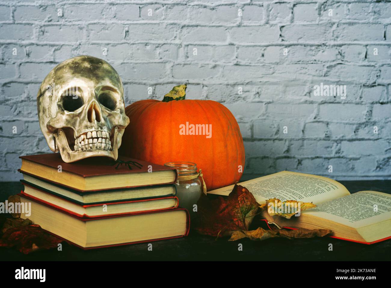 Concetto dei libri di Halloween. Libri, cranio, zucca di Halloween e foglie autunnali su un tavolo di legno. Sfondo concetto di Halloween Foto Stock