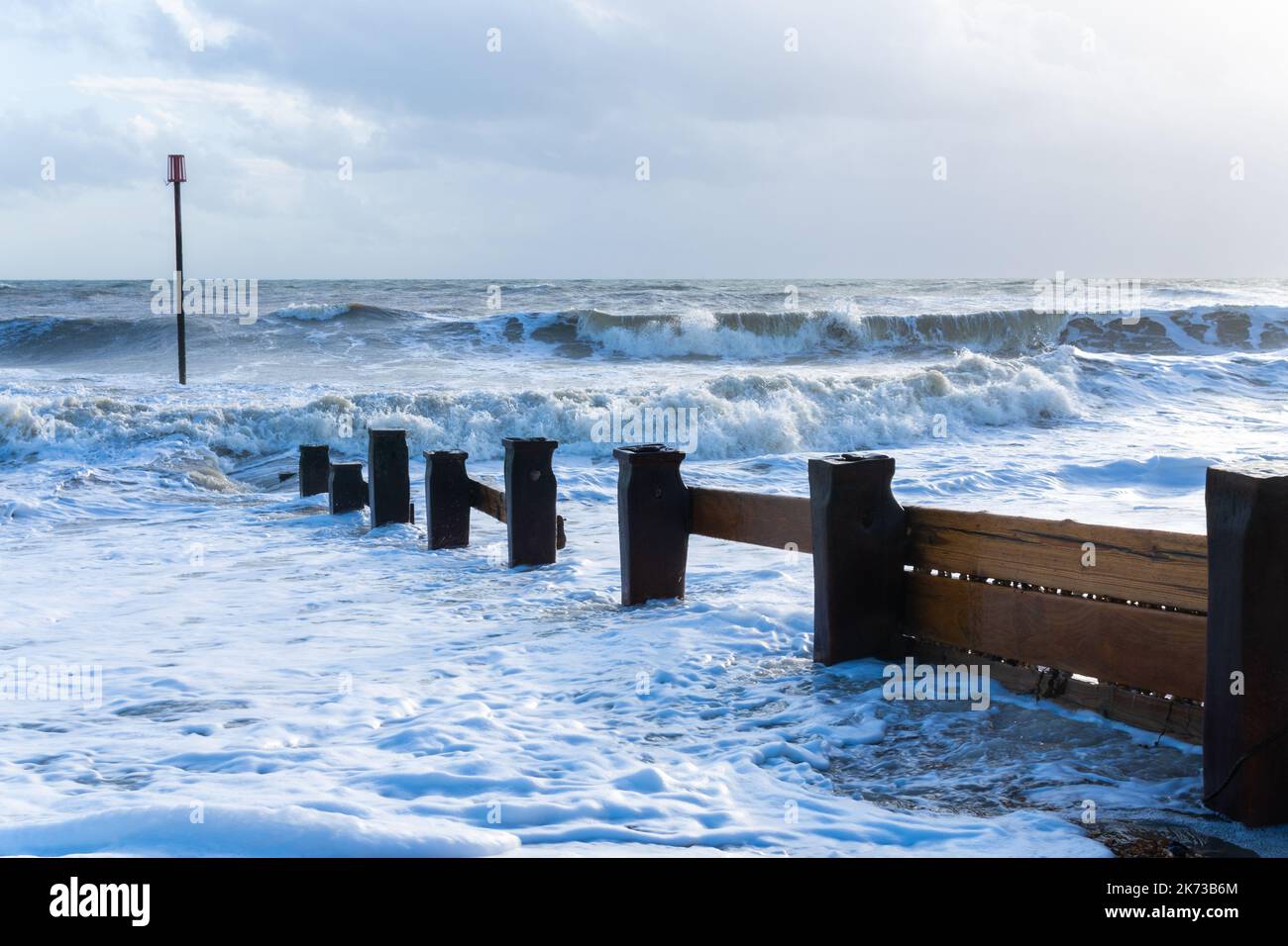 Onde che si infrangono sulla spiaggia di Bexhill-on-Sea con nuvole tempesta e una spiaggia groyne Foto Stock