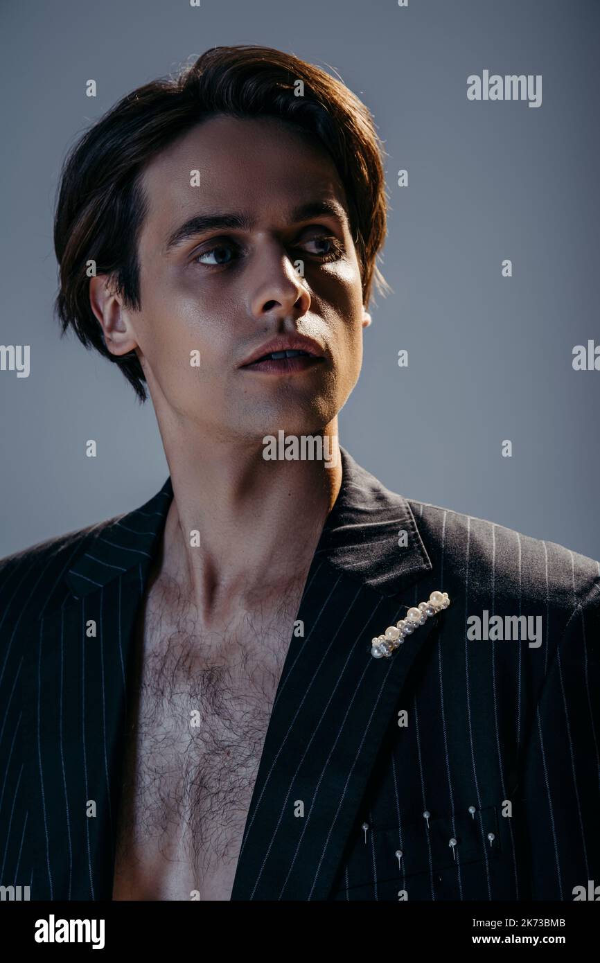 ritratto di bruna uomo con petto peloso e blazer elegante su grigio scuro Foto Stock