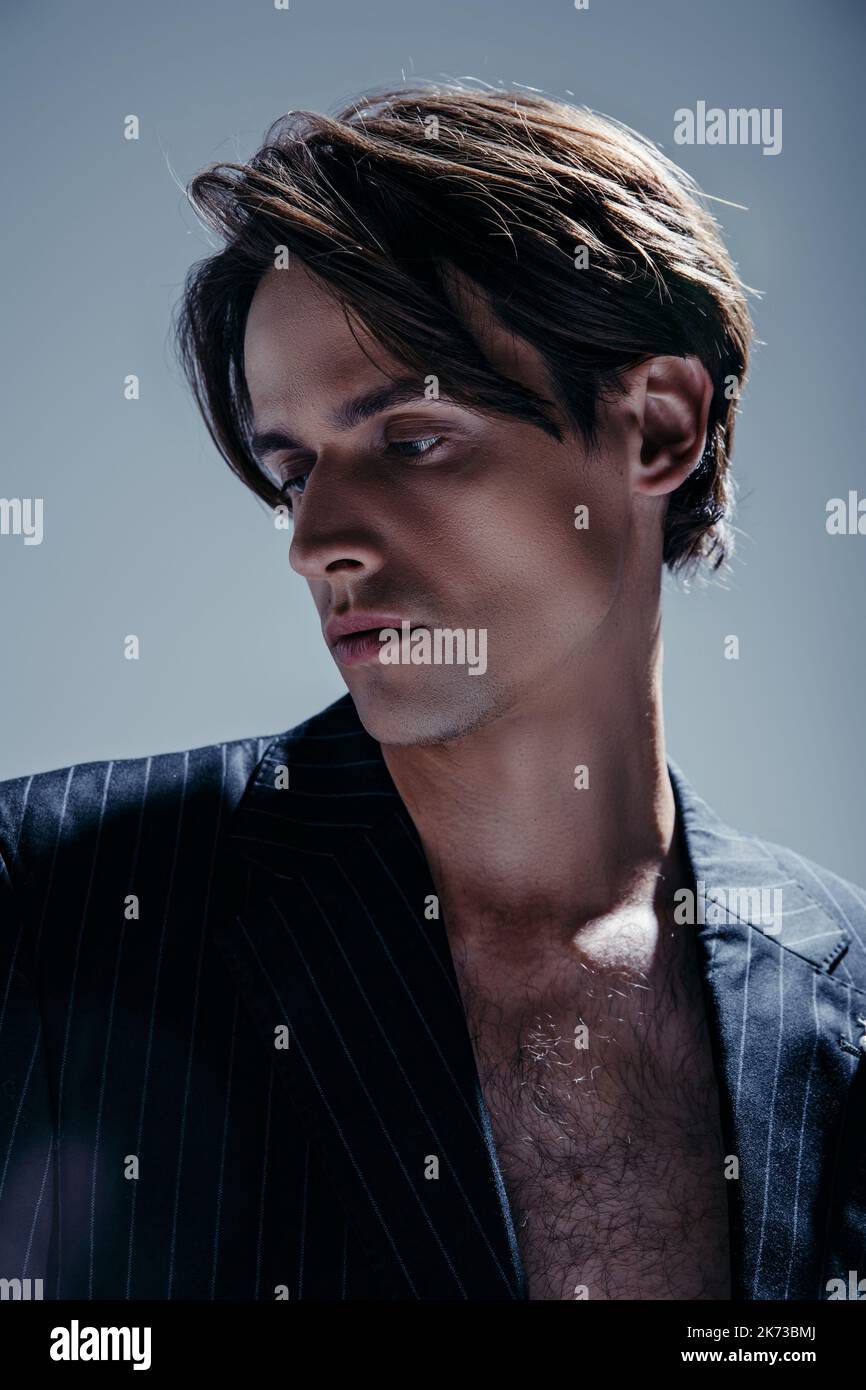 ritratto di bruna uomo con petto peloso che posa in elegante blazer isolato sul grigio Foto Stock