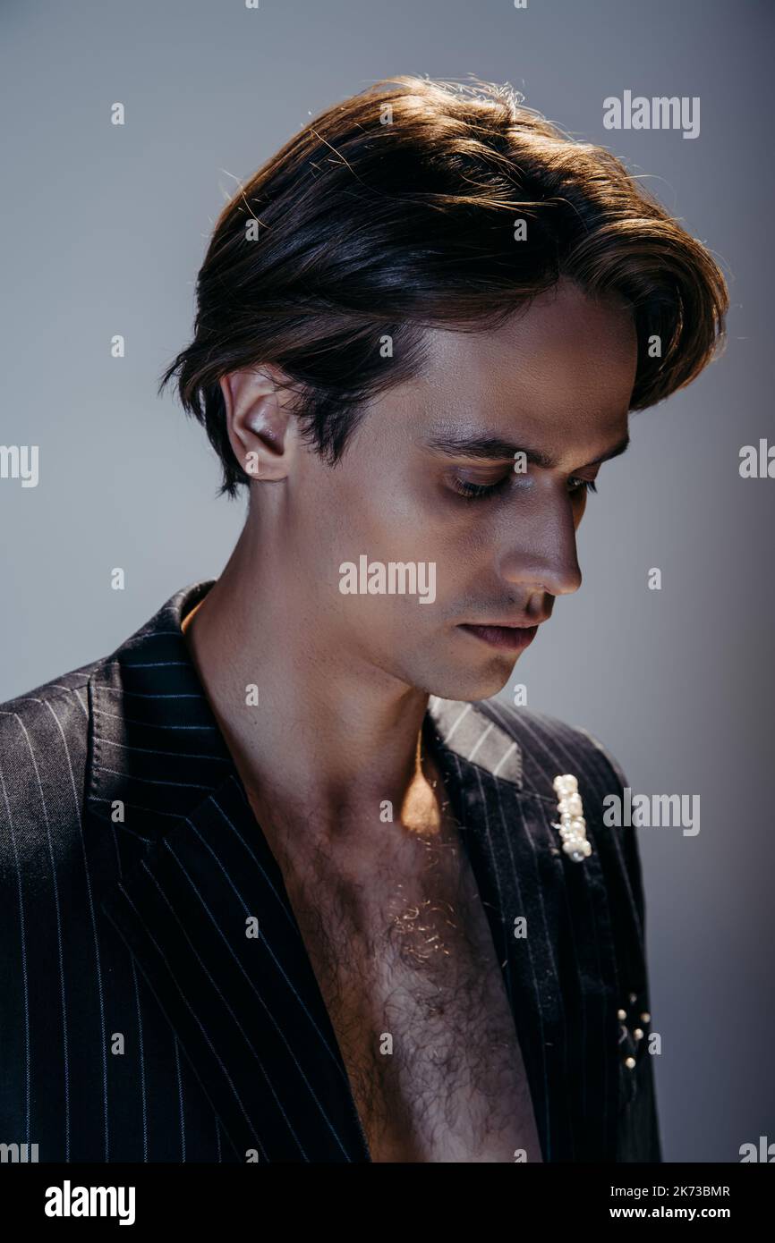 ritratto di bruna uomo con petto peloso e elegante blazer a righe su grigio scuro Foto Stock