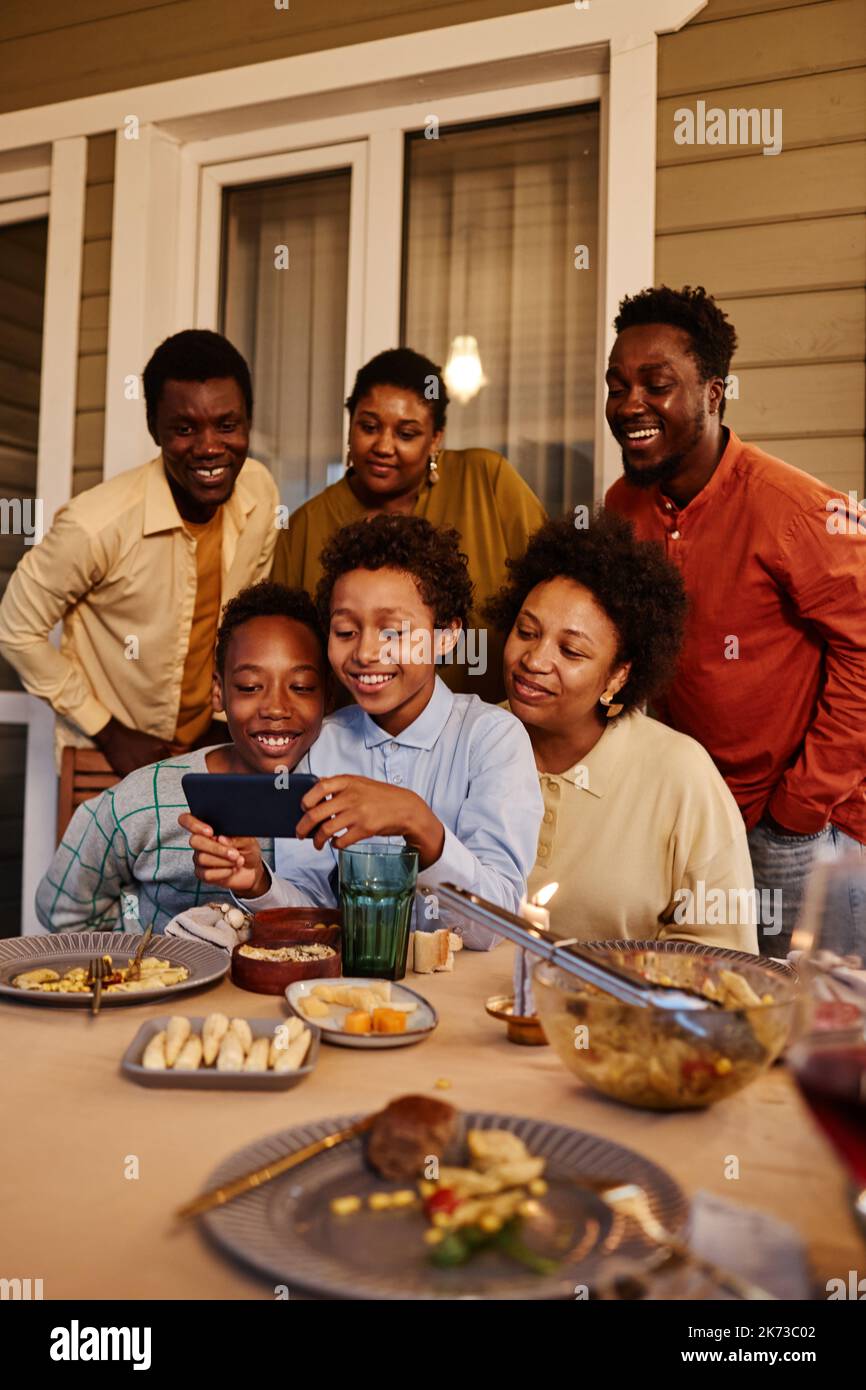 Ritratto verticale di felice famiglia afro-americana scattando foto selfie sulla terrazza della casa in serata Foto Stock