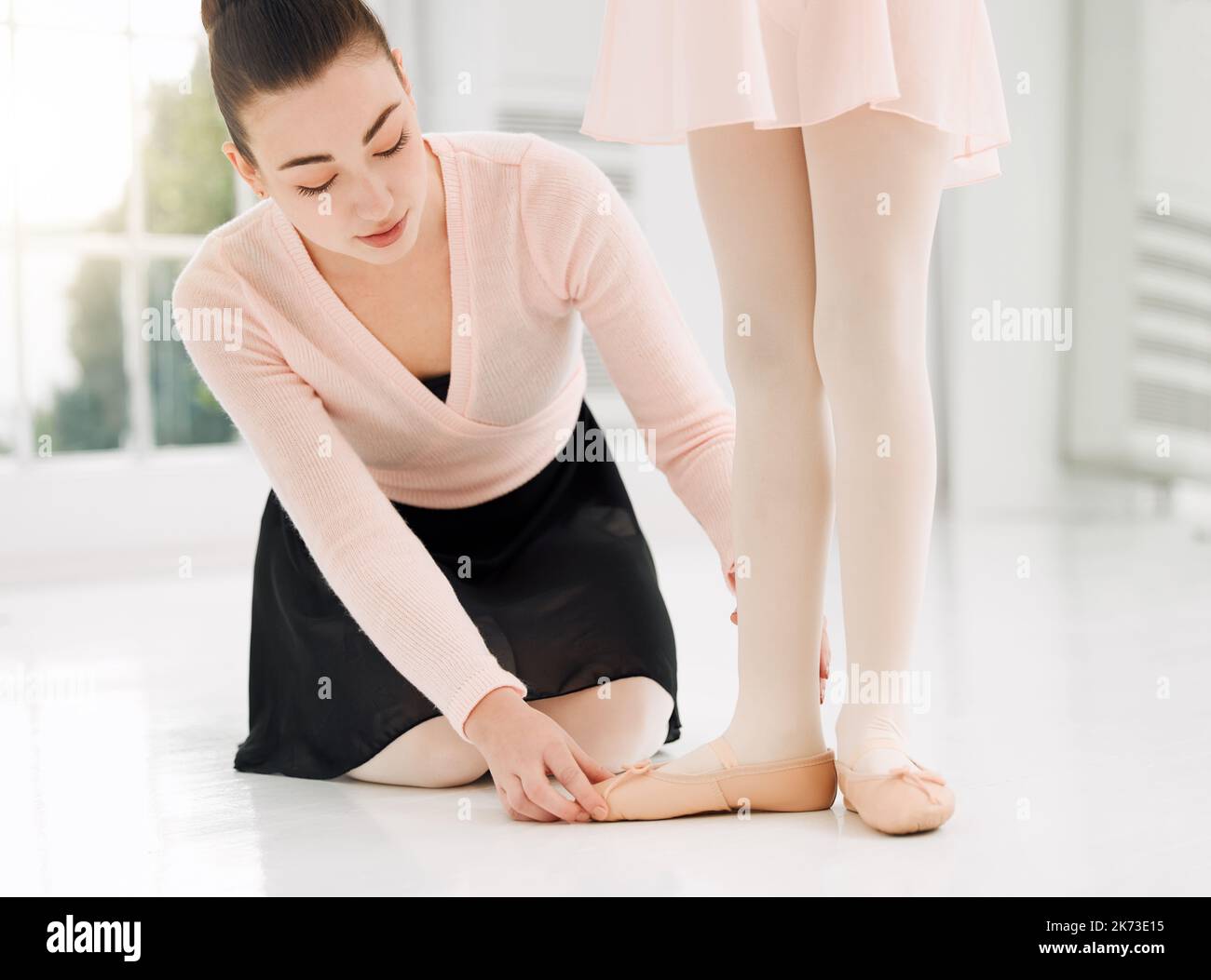 Perfezionare la sua arte un insegnante di balletto che assiste uno studente con la sua posizione in uno studio di danza. Foto Stock