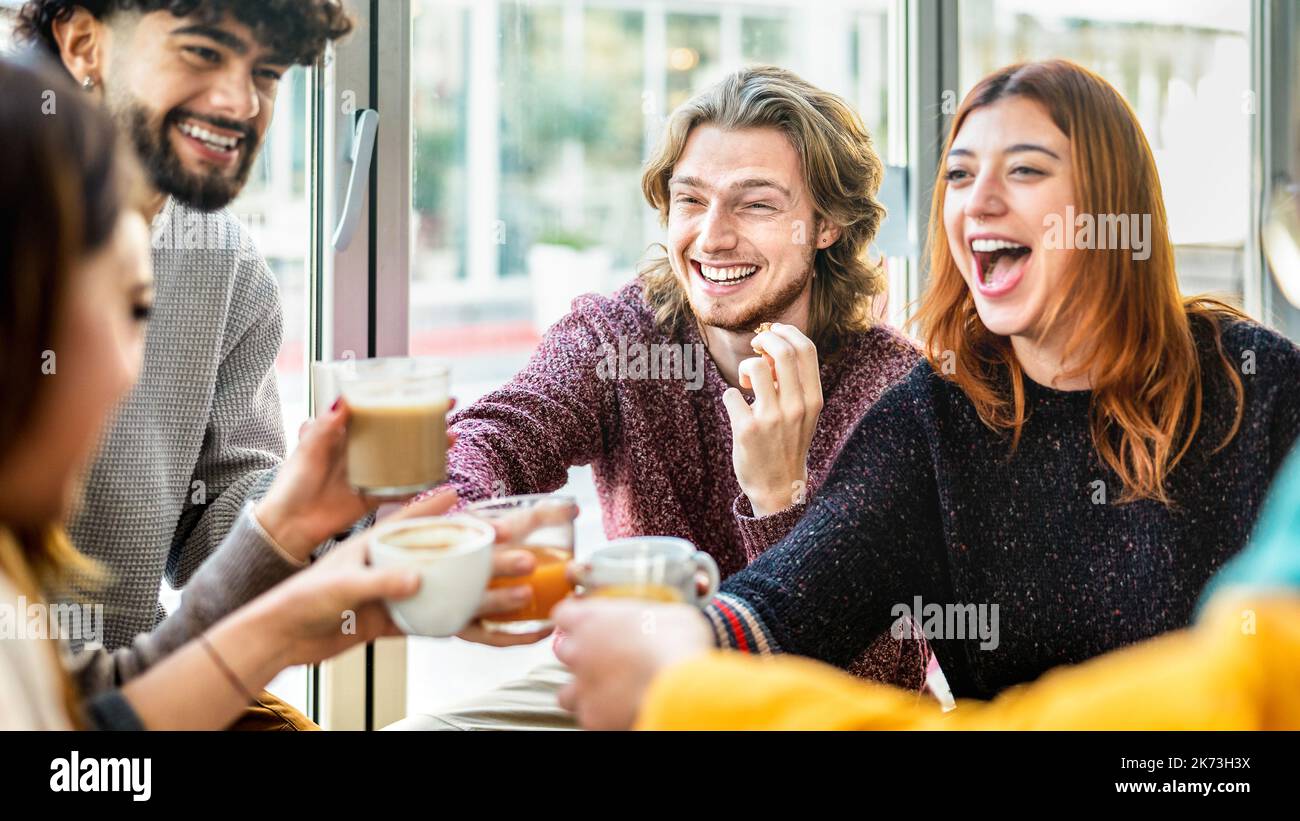 Gruppo di amici che brinda latte al patio del bar del caffè - persone che parlano e si divertono insieme al ristorante cappuccino - concetto di stile di vita con un ragazzo felice Foto Stock