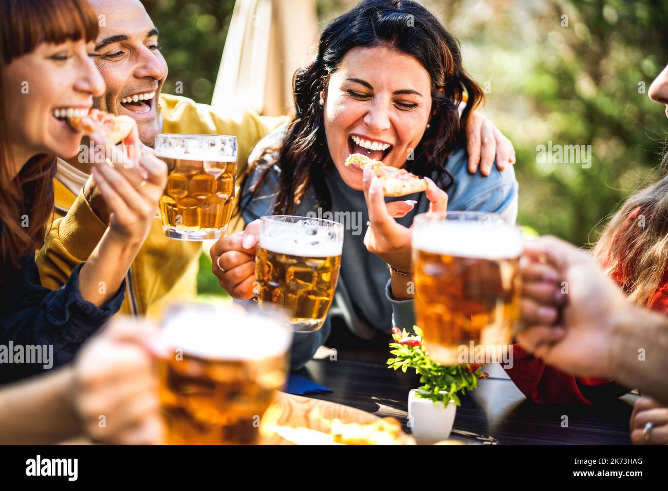 Amici felici che mangiano la pizza alla birreria all'aperto - bevanda concetto di stile di vita con i giovani che si godono il tempo di bere insieme e divertirsi alla birreria Foto Stock